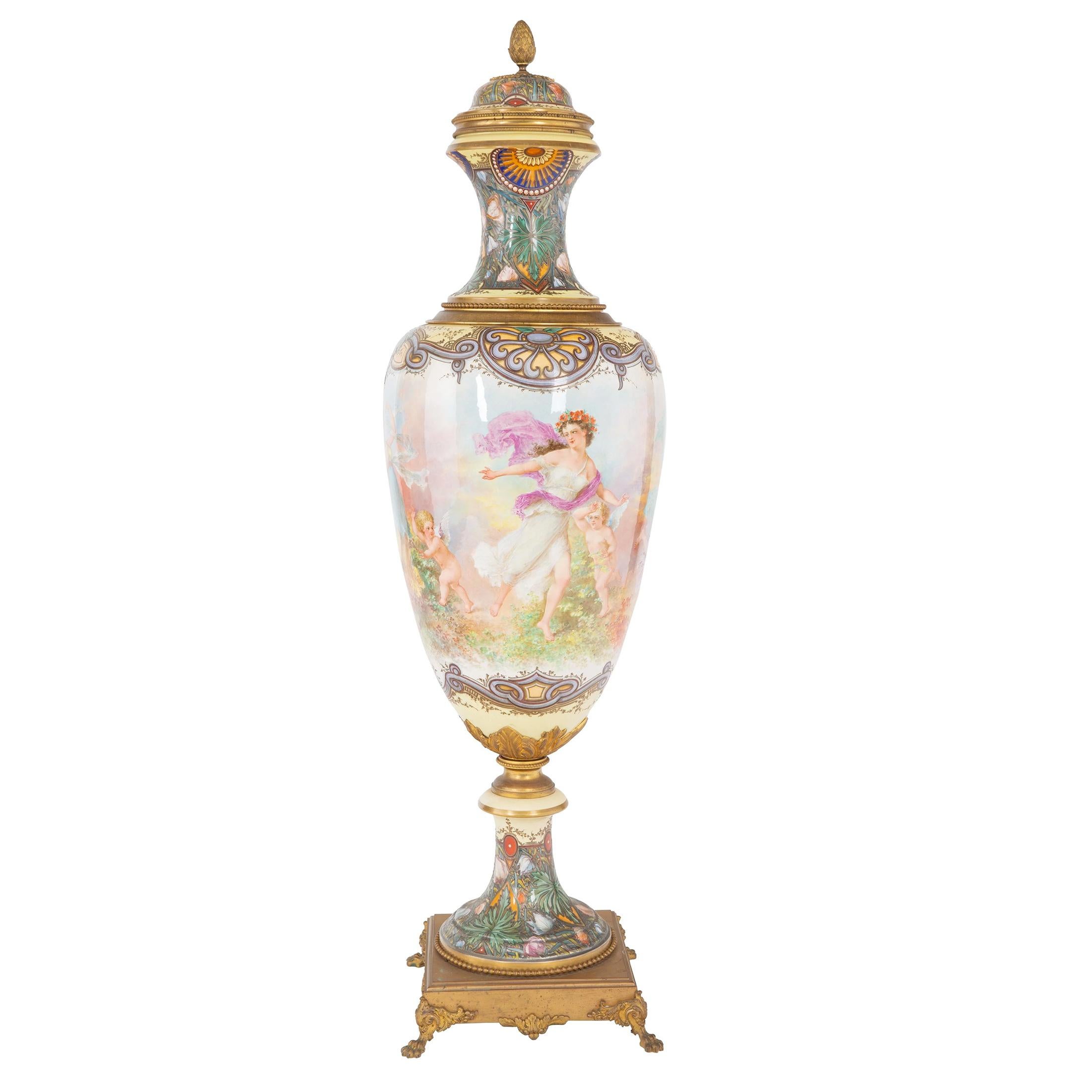 A stunning monumental gilt bronze-mounted Sèvres style vase and cover, painted with continuous scene of beautiful women adorned with flowers in loose clothing dancing with putti. Featuring Art Nouveau style floral and foliate scrolls in the neck and