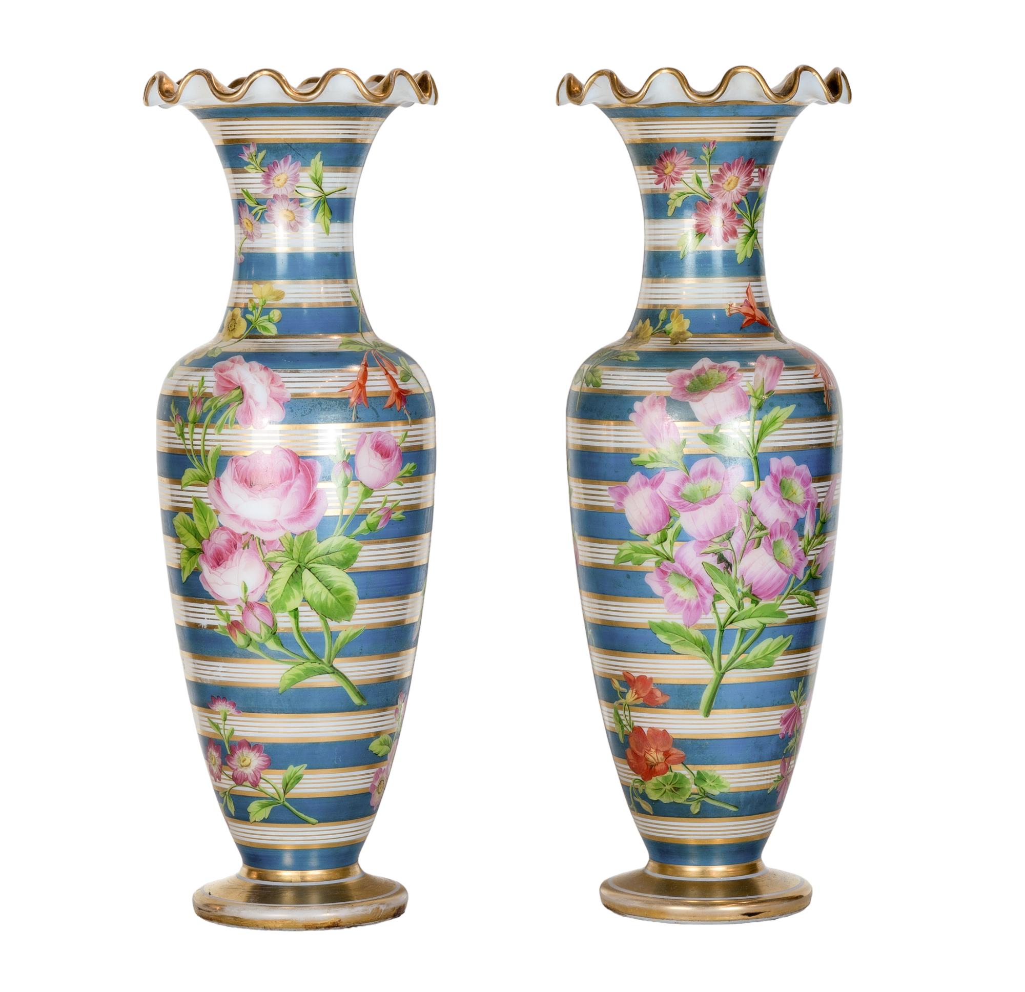 Une opulente paire de vases en verre opalin de Baccarat peints à la main. Enveloppés de rayures céruléennes et dorées, le ventre et le col des vases sont ornés de douces fleurs peintes à la main et d'une frise dorée.  Chaque fleur éclate avec une