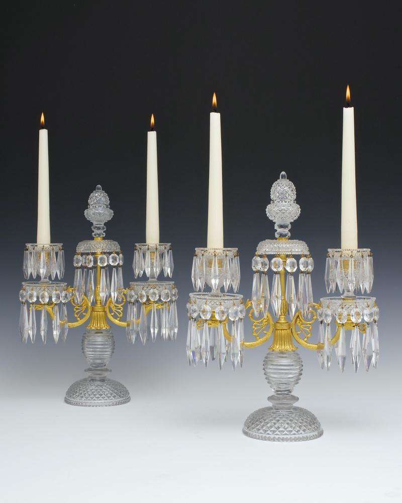 The diamond and step cut base supporting an ormolu twin branch of dragon form this surmounted by richly cut drop hung drip pans and candle nozzles the candelabra centred by drop hung drip pan and diamond cut acorn finial, the candelabra hung with