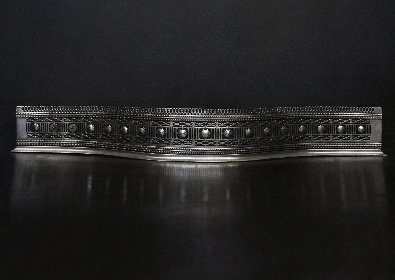 A fine quality serpentine fender in the Georgian manner. The pierced fret with engraved paterae, beading and diamond motif throughout. Polished steel. English, 19th century.

Measures: External width: 1255 mm 49 