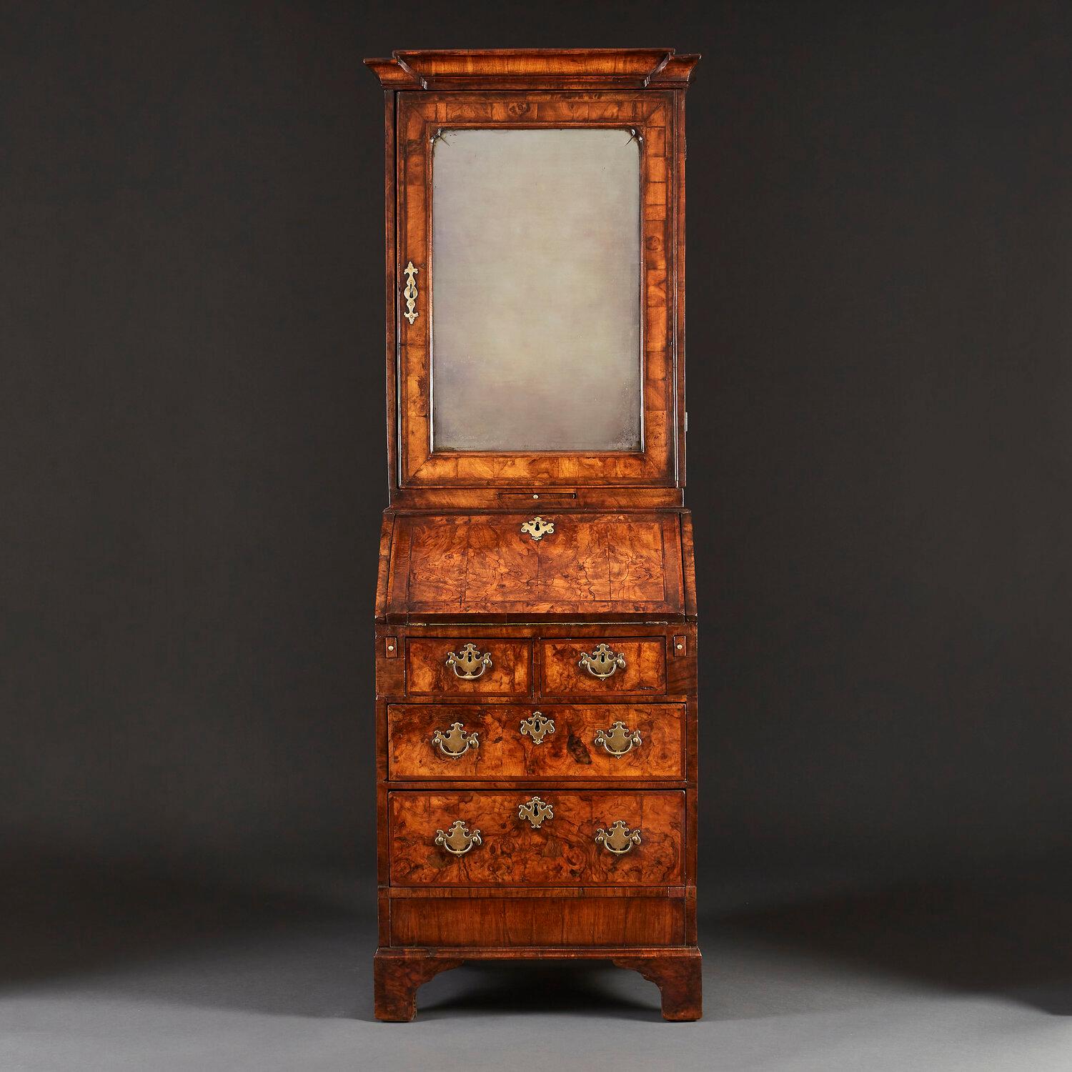 A fine Queen Anne period burr walnut bureau bookcase of narrow proportions, the upper body with a beveled mercury mirror to the door, opening to reveal five drawers to the interior, with fine burr walnut veneer. The lower body opening with drop leaf