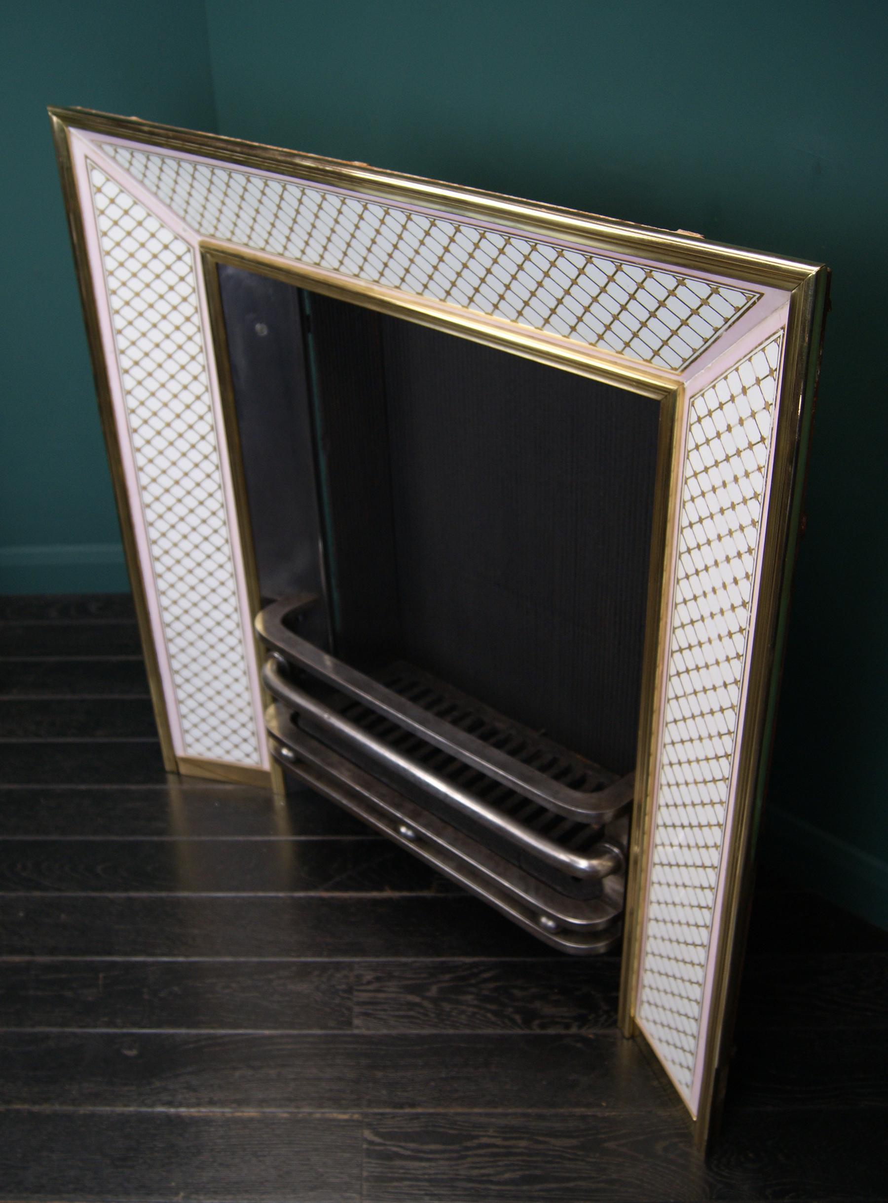 A fine Regency full register grate with pink and white ceramic panels. The ceramic panels are adorned with gold lattice-work framed with a pink border, set between bold brass mouldings. The removable front basket is formed in polished wrought-iron