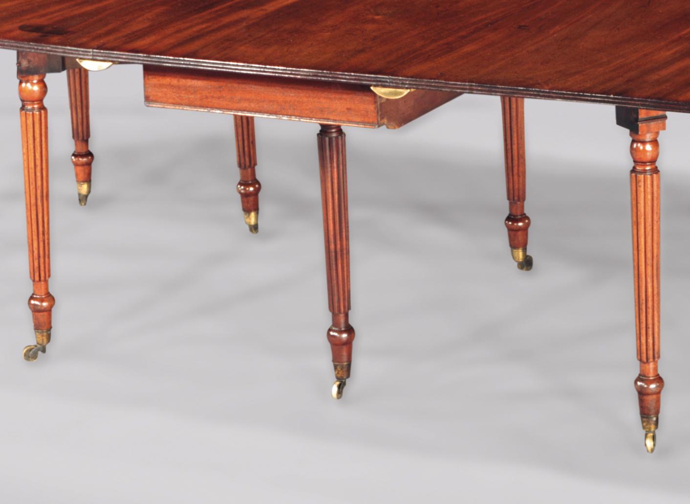 A good quality early 19th century Regency period golden mahogany reeded edged dining table having drop flap gate-leg actions to centre and ends, fitted with four removable leaves, supported on slender turned reeded legs ending on brass castors.