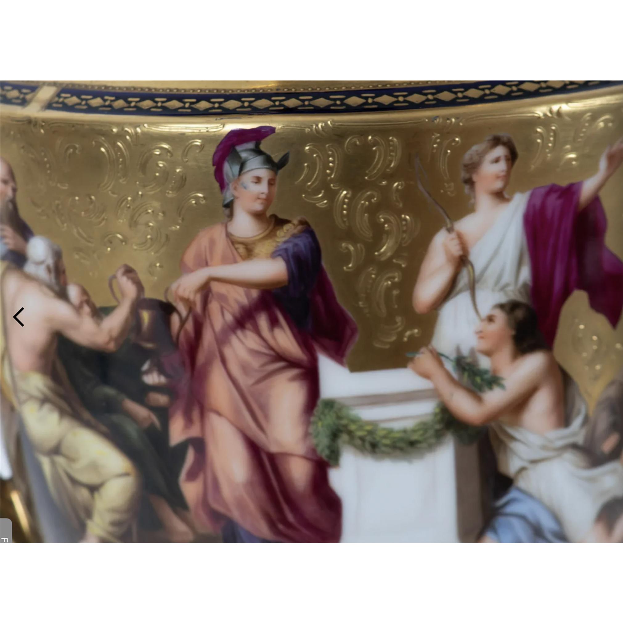 A Fine Royal Vienna Porcelain Urn. The belly of the urn depicts an unknown scene of a man in purple nobility robes, standing before a podium as a group offer him a box and a goat to be sacrificed and more. Elaborate gilded painting throughout with