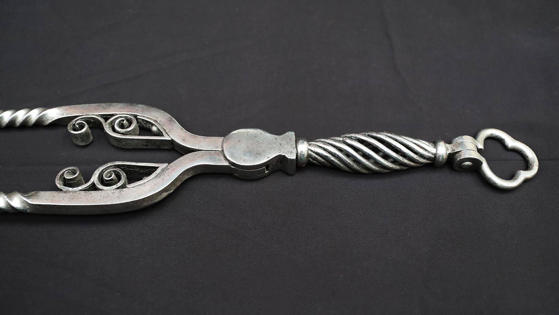 A fine set of polished wrought-iron fire tools with hinged clover-leaf handles. The set comprises of tongs, poker and shovel all with basket twist detail on lower handles and barley twist to shafts. The tongs feature scrollwork and clover-shaped