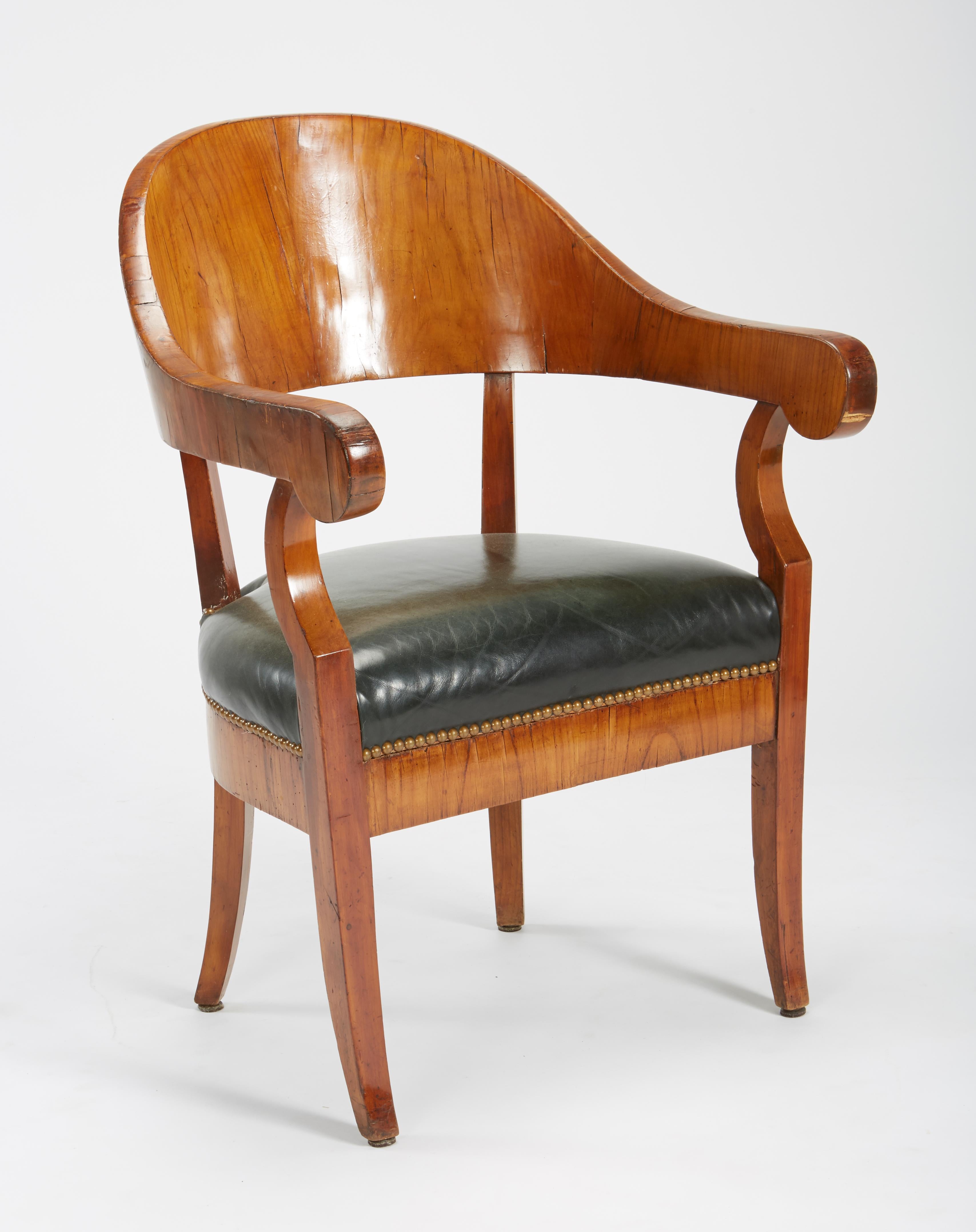 A fine set of six Austro-Hungarian Biedermeier fruitwood chairs, early 19th century, including an associated armchair, each sidechair with a crescent-shaped crest rail outlined in ebony, the verde antico and parcel gilt splat carved with a torch