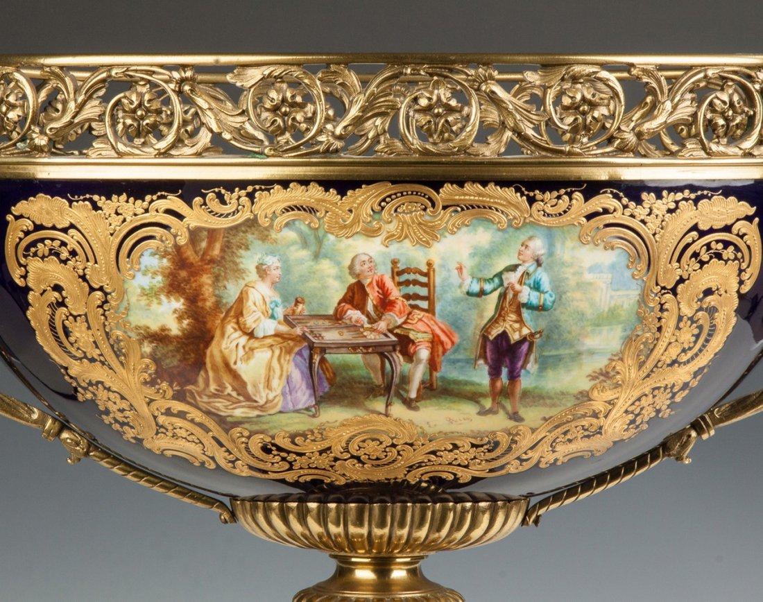 A fine artist-signed, hand painted ormolu-mounted Cobalt blue porcelain centerpiece with winged seraph handles.

Origin: French
Date: 19th century
Dimension: 21 in x 23 in.