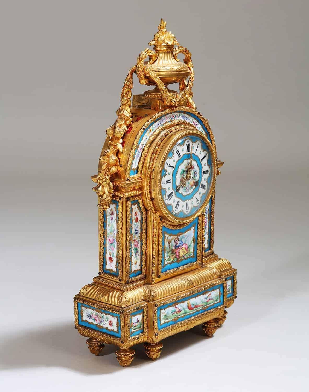 A rare and very fine 19th century Napoleonic era Sevres Porcelain mantel clock, The richly chased ormolu gilt bronze body inset with 11 panels of porcelain with floral scenes, birds and figures within blue celeste borders and the clock face with