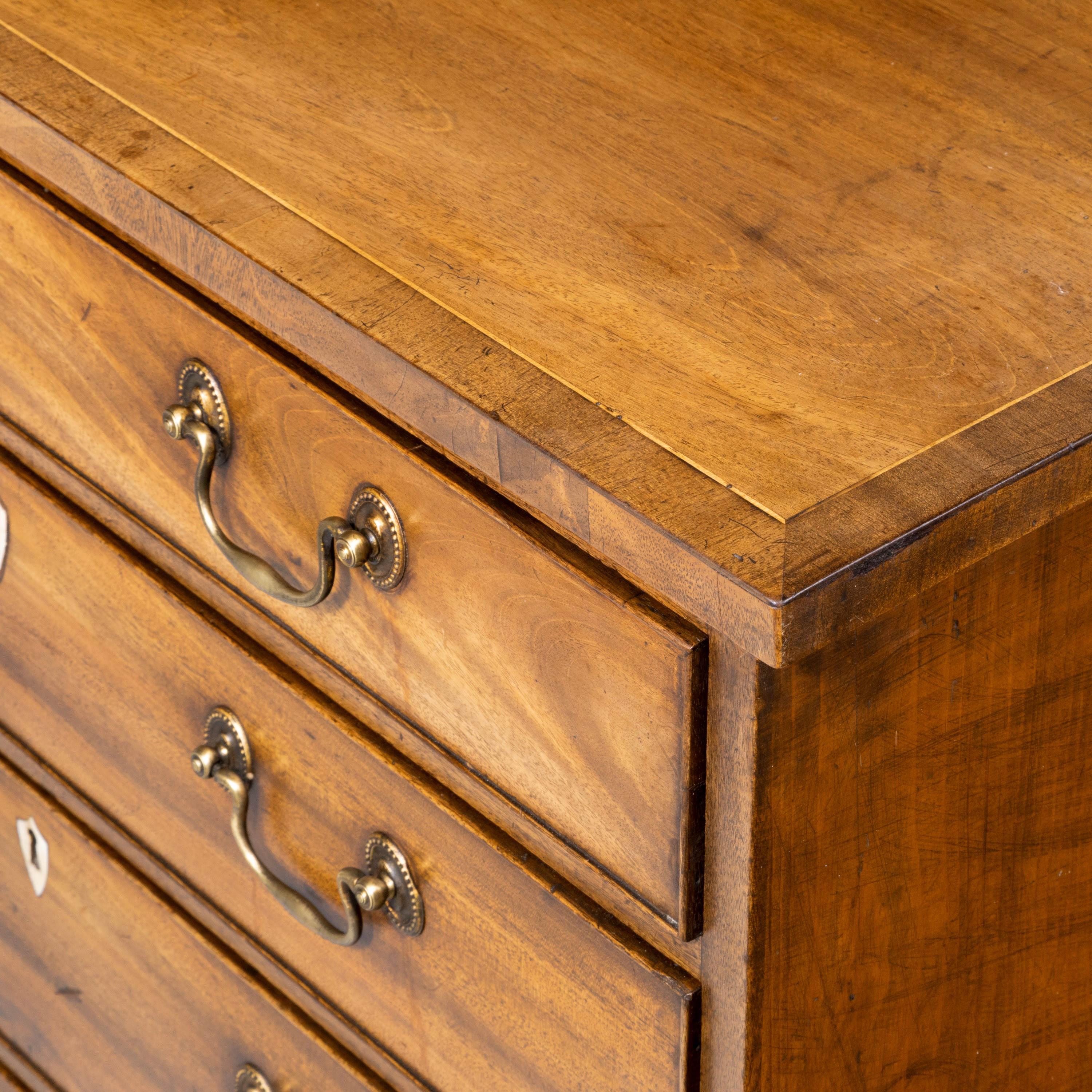 A final Sheraton period chest of drawers of very small proportions. On high original bracket feet and retaining the original swan neck handles with traces of gilding.
       