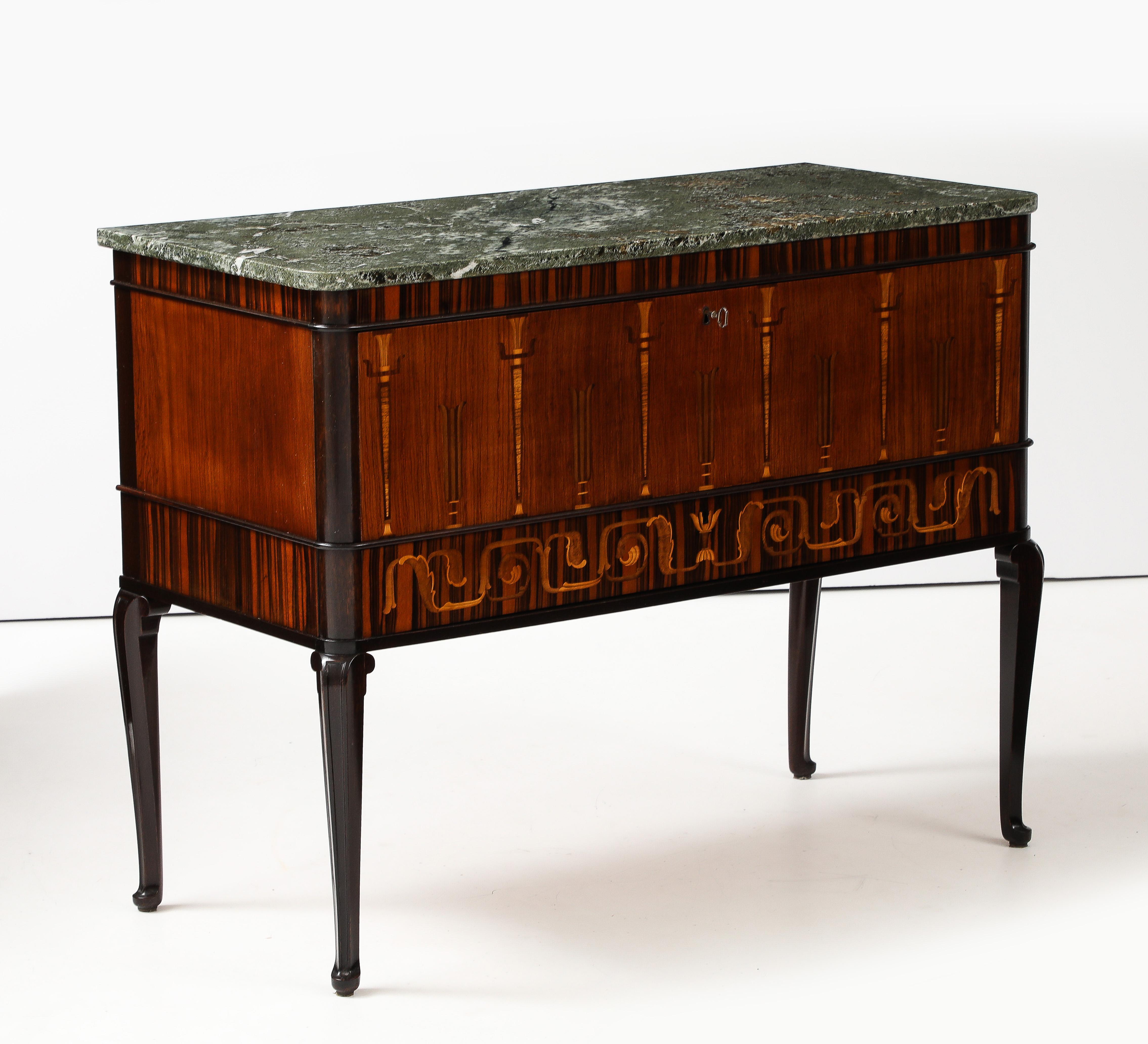 A fine Swedish Grace chest of drawers, circa 1930s, the Kolmards marble top above a cross banded palisander frieze, the center deep drawer decorated with fruitwood inlaid torche, the lower drawer with Neoclassical inspired leaf and scroll inlays,