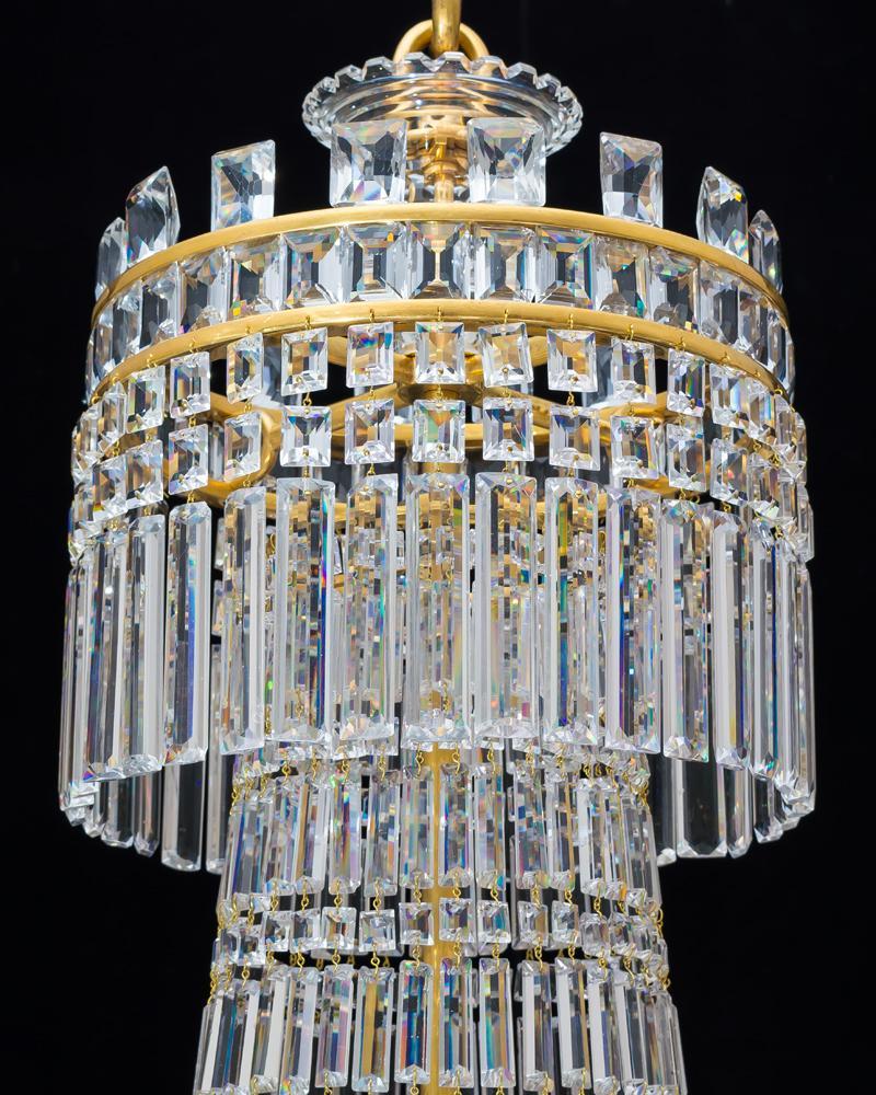 A fine ormolu-mounted Regency chandelier of classic tent and basket design the tent terminating with drop hung double band corona, this inserted with emerald cut segments and mounted further with emerald cut soldiers, the main double band ring of