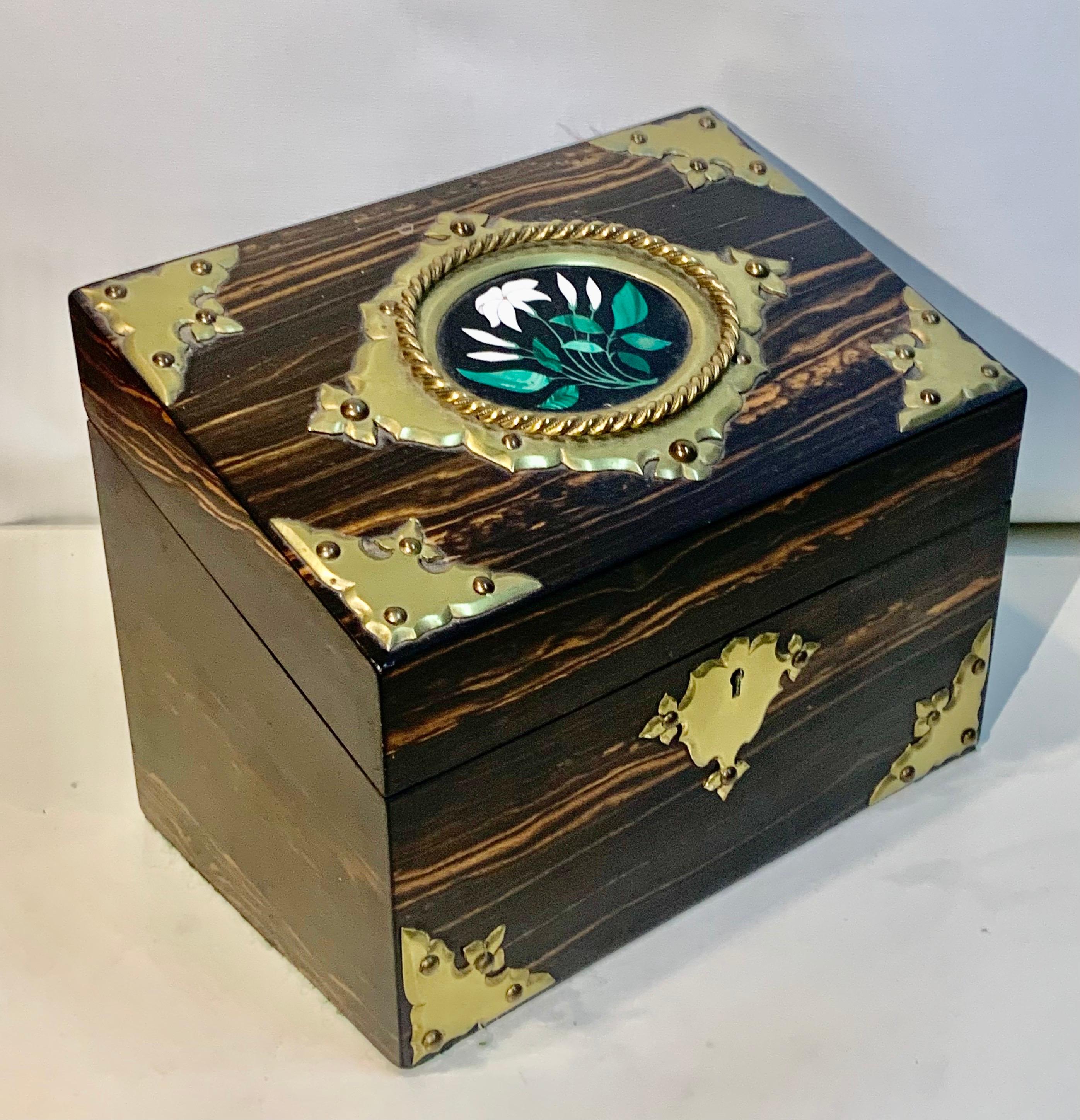 A fine Victorian Coromandel stationary box, the sloping hinged cover inset with a pietra dura panel depicting flowers, within a gilt metal mount lifting to reveal a fabric lined compartmented interior. The condition is very good and its ready to use.