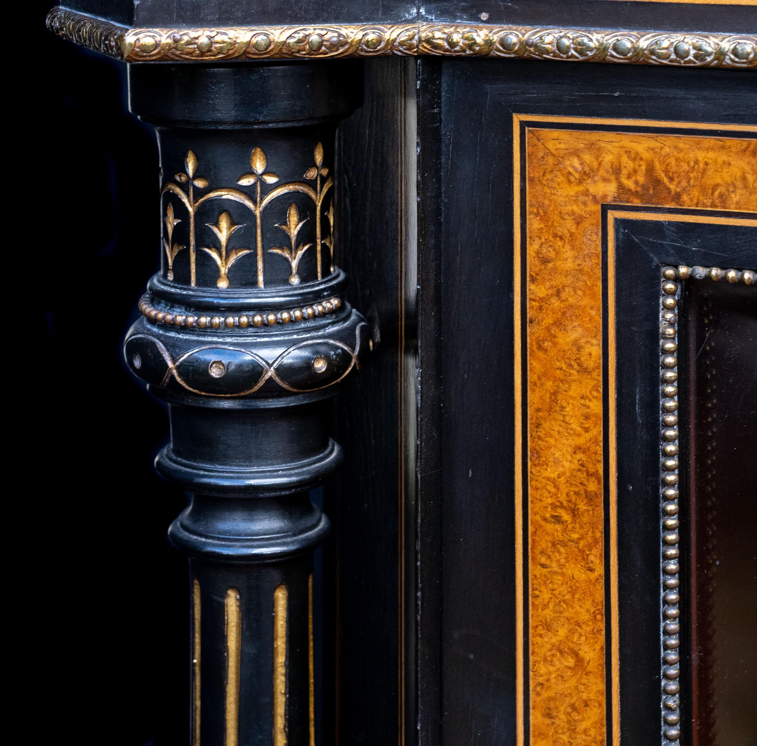 A very fine three door Victorian, ebonized, ormolu and inlaid Credenza. The three doors, two of which are glazed are separated by turned, carved, gilded and ebonised columns, supporting a delicately inlaid frieze with ormolu detail. The central door