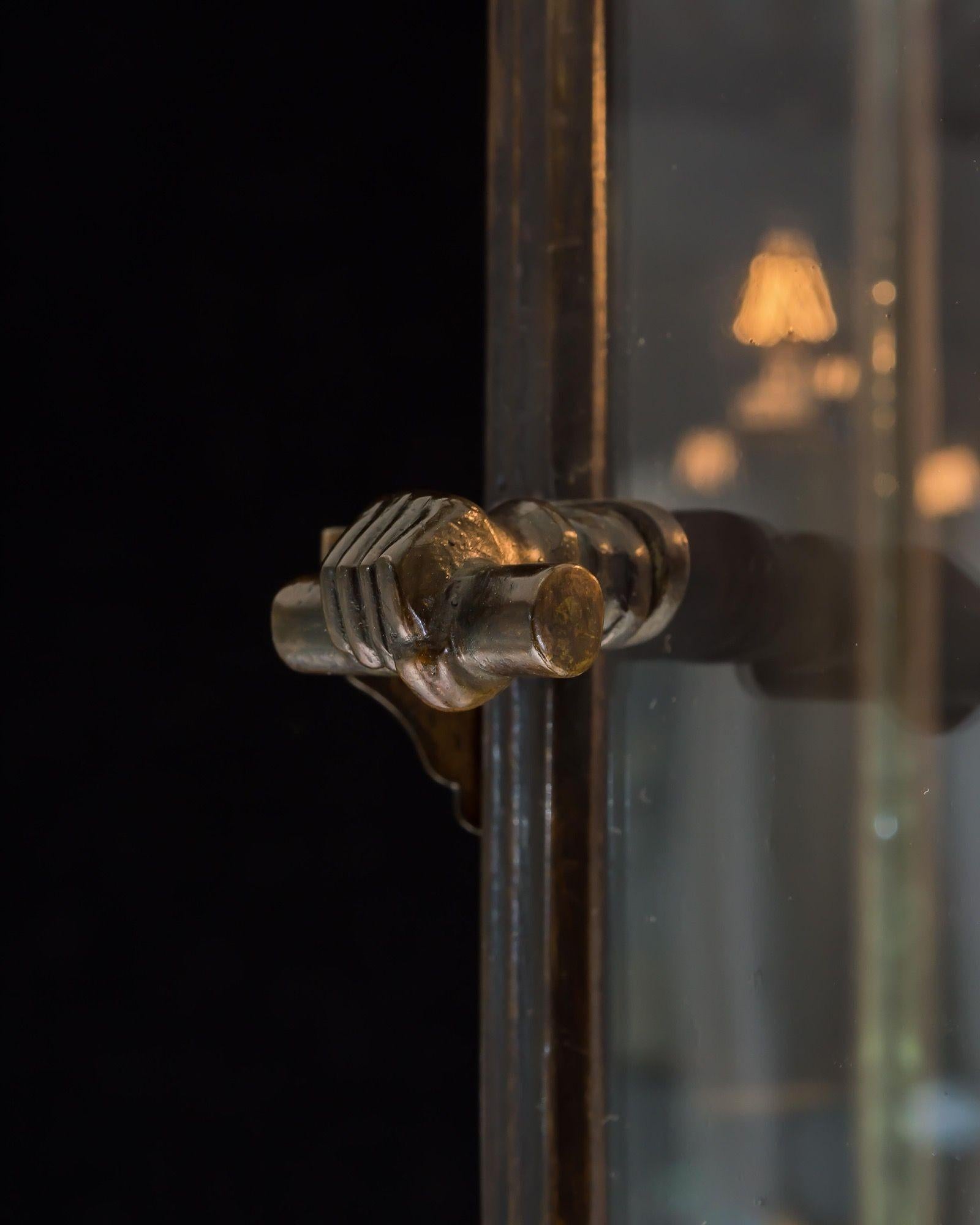 Der bronzierte sechseckige Rahmen mit offener Tür ist mit einer klassischen Schnecke in der Hand versehen. Der Rahmen ist mit vergoldetem Metallwerk in Form von Blättern verziert, an dem ein dreiflammiger Kandelaber hängt.