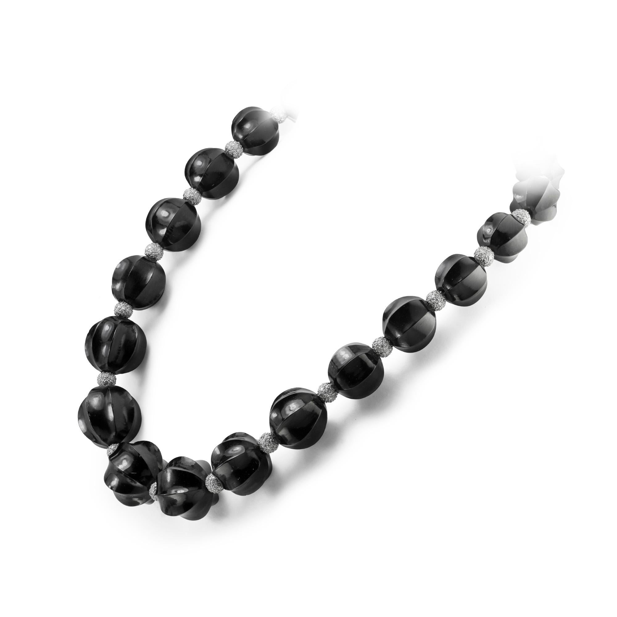 A fine vintage jet and diamond-set bead necklace, consisting of twenty-one graduated from the centre fluted jet beads, measuring from 14 to 17mm in diameter, stung with twenty diamond-set white gold beads in between, all to a diamond-set ball clasp,