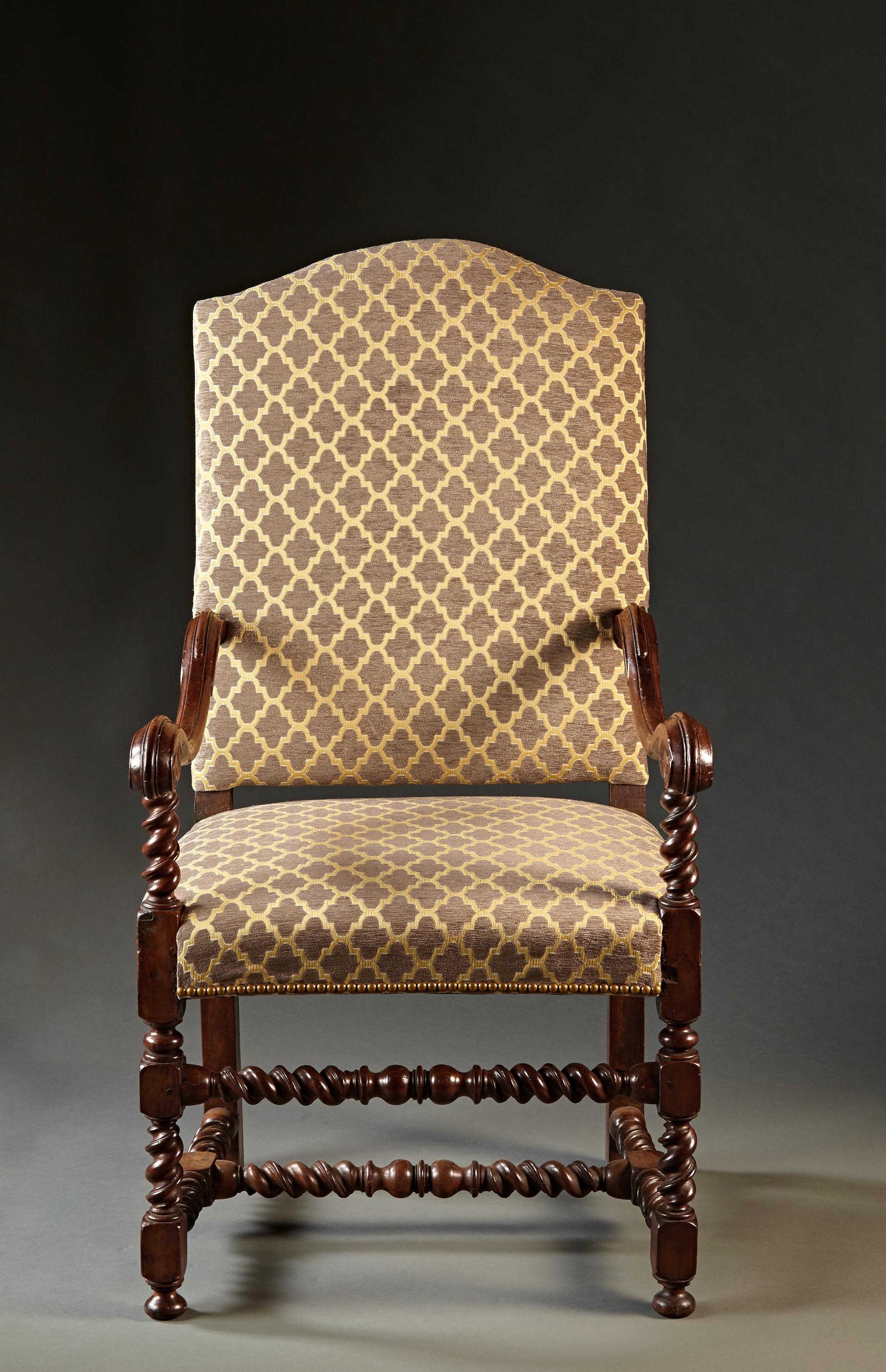 A walnut Louis XIII period armchair with carved, scrolled arms, spiral turned legs and 