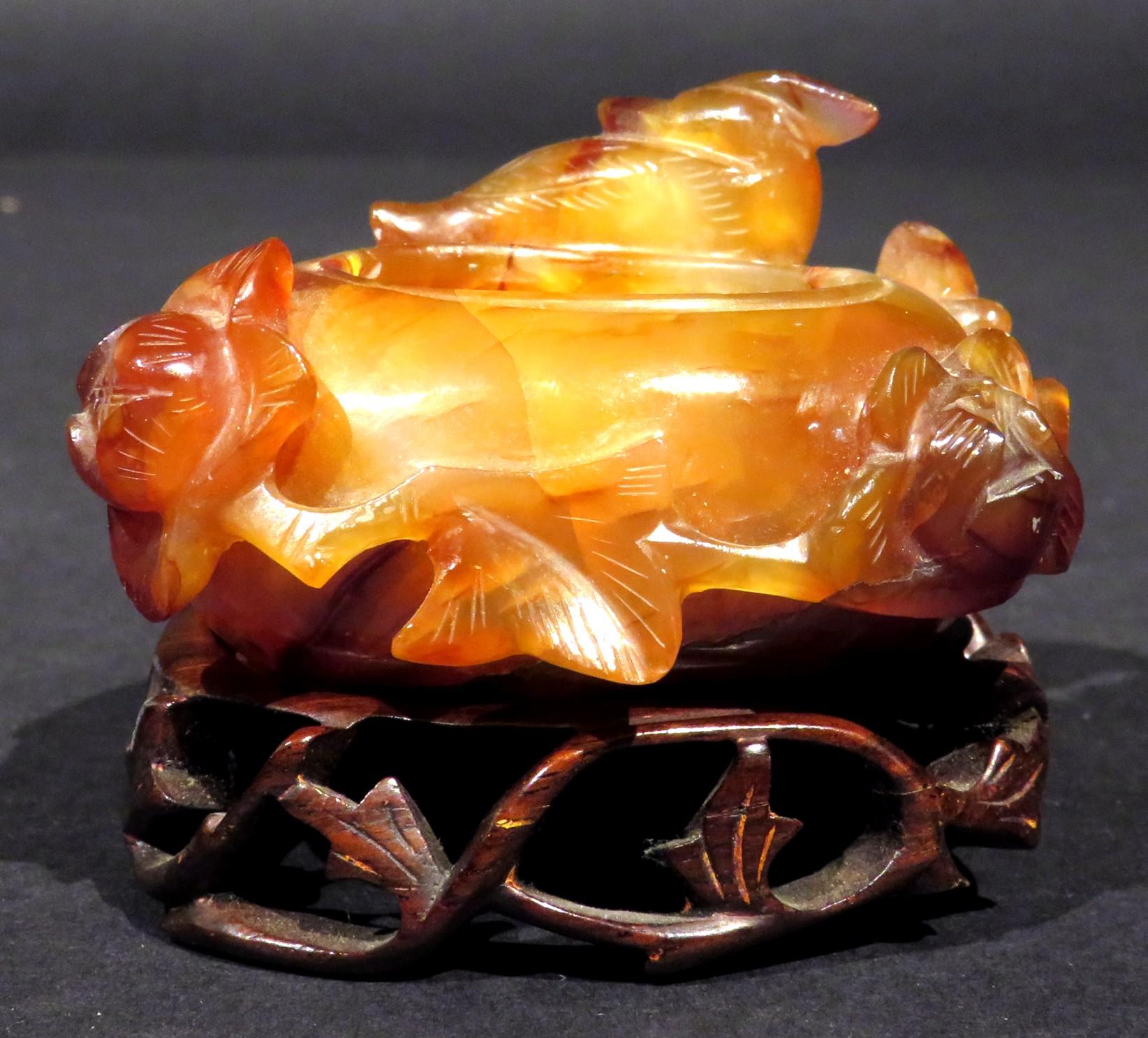 The finely carved & pierced russet agate body decorated with the figure of a Phoenix & trailing, flowering vines surrounding the open well, raised overall upon a finely carved & pierced wooden stand.                                                  