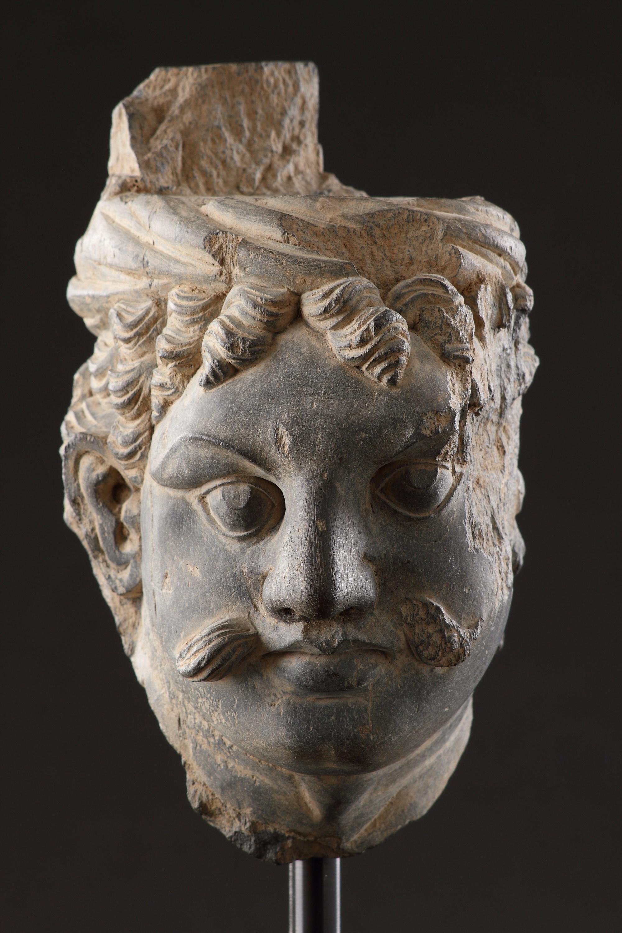 A Finely Carved Gandhara Head of ‘Atlas’
Grey schist
India
3rd - 4th Centuries AD

SIZE: 19cm high, 11cm wide, 12.5cm deep - 7½ ins high, 4¼ ins wide, 5 ins deep

References  
Pratapaditya, Pal; ‘Asian Art at the Norton Simon Museum’, Vol. l; Art