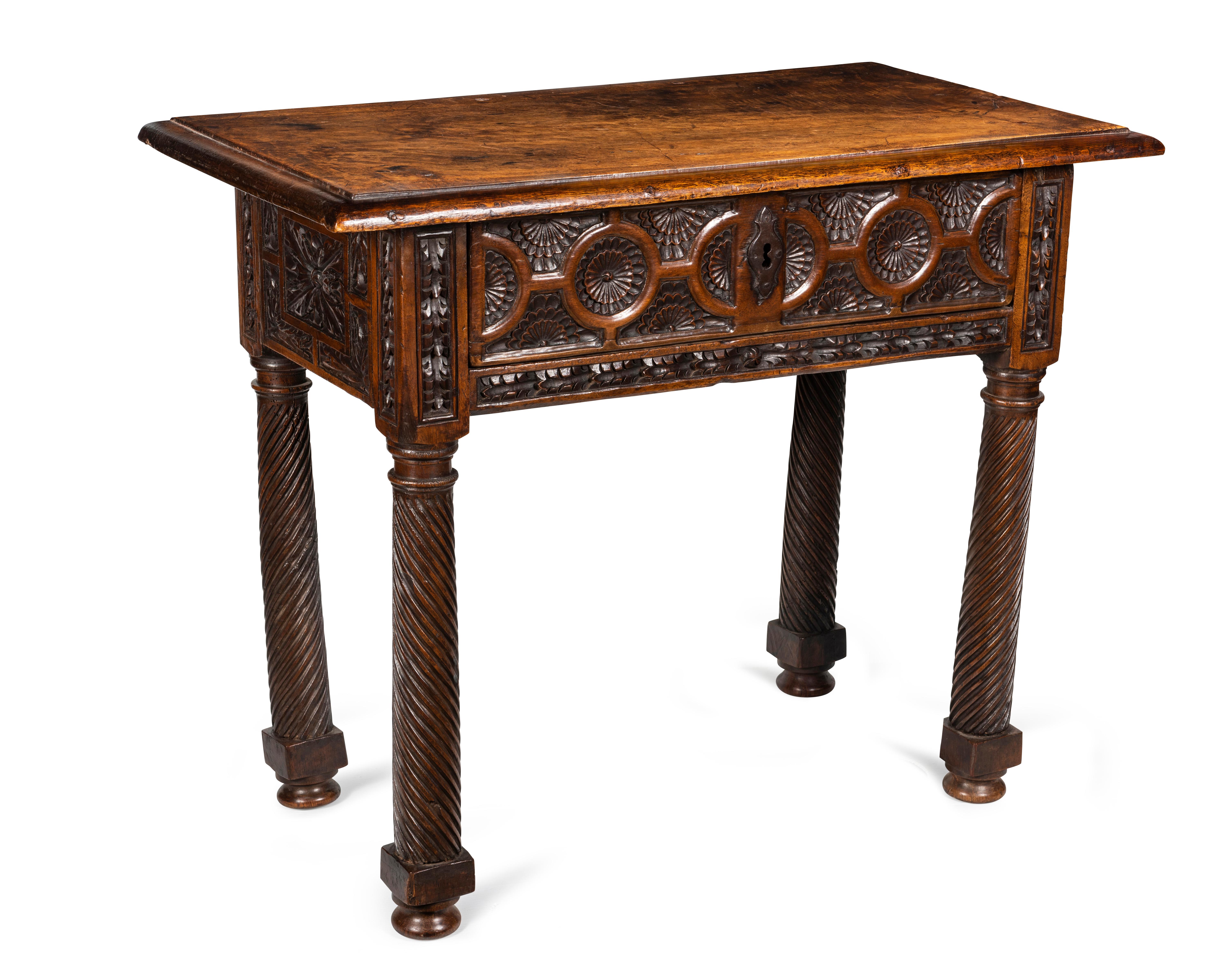 The single plank top with ovolo moulded edge over recessed single drawer with carved stylised rosettes and rings, centred with iron cartouche shaped escutcheon and flanked by leaf carved standards, continuing to side frieze carved with leaf and