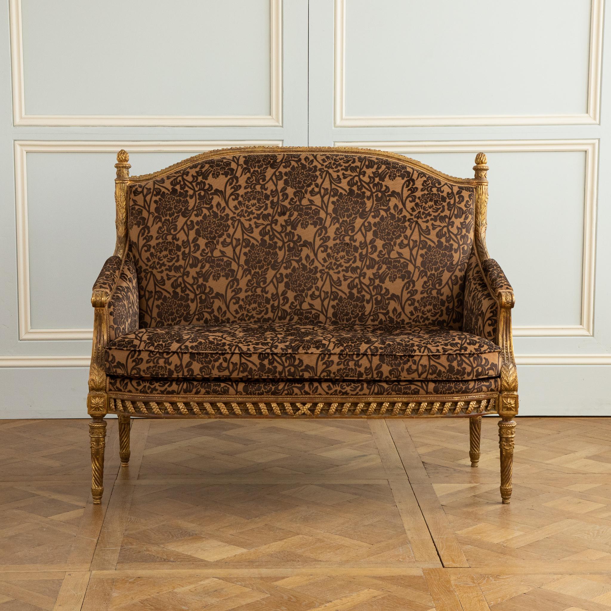 A Louis XVI style two seater sofa featuring exquisitely fine carving from LML's most master carvers. The piece is a replication of an original; made to the highest standard and finished in a hand gilded patina which has been given an old gold,