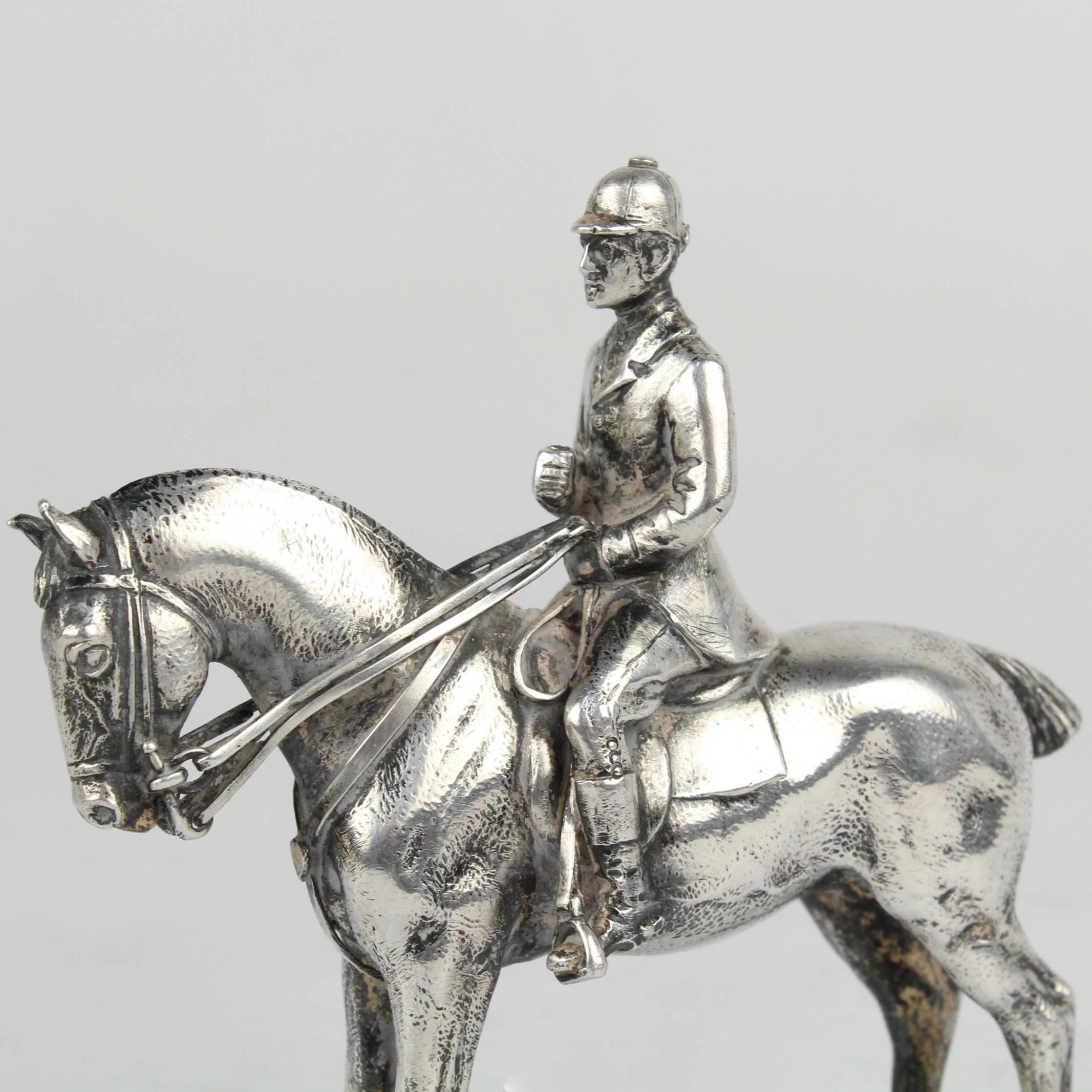 A very finely cast silver horse and rider sculpture. 

The horse and rider appear set to perform dressage. The rider's right hand is raised (and perhaps lacks a whip.)

The sculpture is unmarked. We believe that the silver fineness is coin or