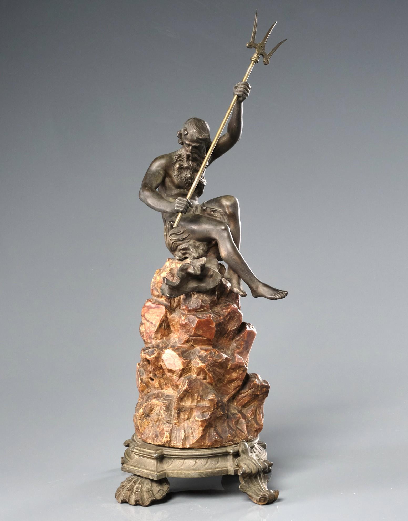 The finely detailed & proportioned cast spelter figure of Neptune, dramatically poised with trident in hand, seated atop a realistically modelled hand carved rocky mound of solid red soapstone. Raised overall upon a circular spelter base on shell