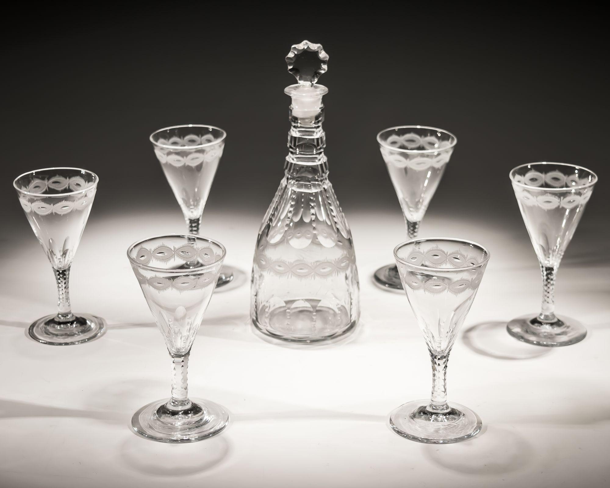 A slice and notch cut spirit decanter with engraved band with six corresponding glasses.

GLASSES

HEIGHT 13cm (5 1/4