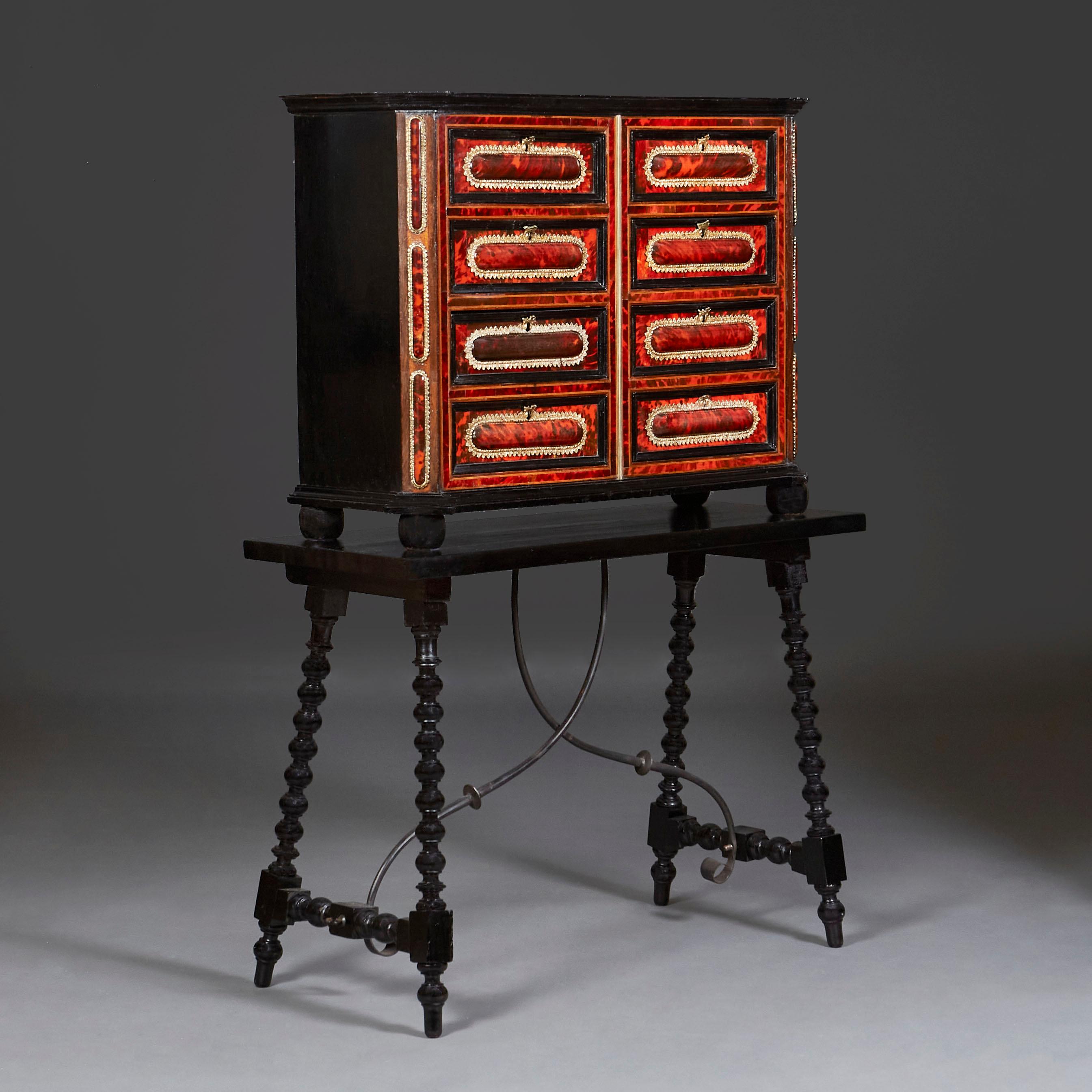 Spanish, circa 1820

An early nineteenth century tortoiseshell cabinet with eight drawers, with fine gilt bronze mounts. Also with ebonised carcass, all supported on four bun feet and mounted on an ebonised stand with barley twist legs and curved