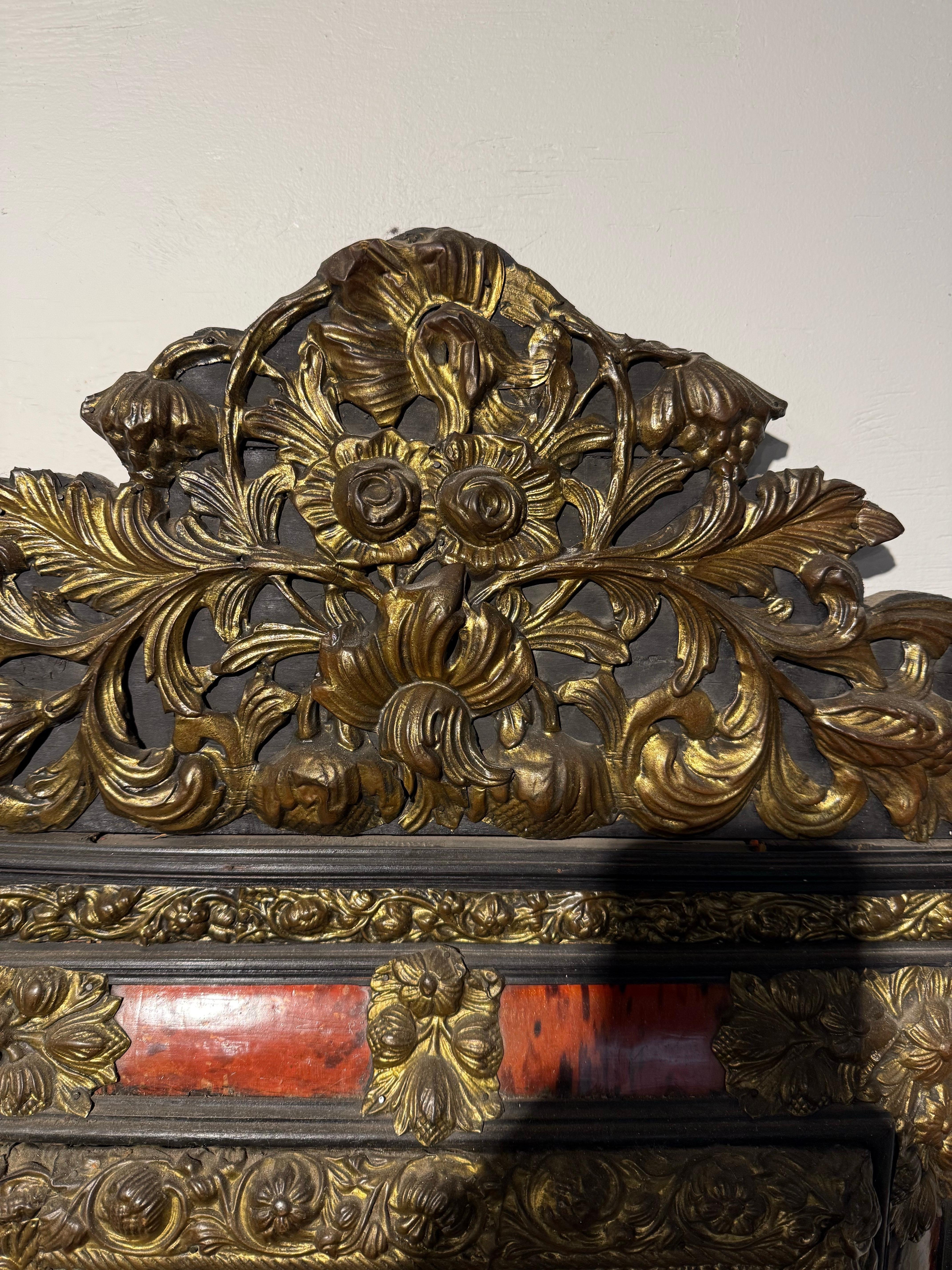 A Flemish Faux Tortoiseshell and Repousse Mirror, 19th Century

Description:
The bevelled glass held within a triple frame, the central frame of faux tortoiseshell with repousse floral mounts to each corner and midpoint, surrounded by an inner and
