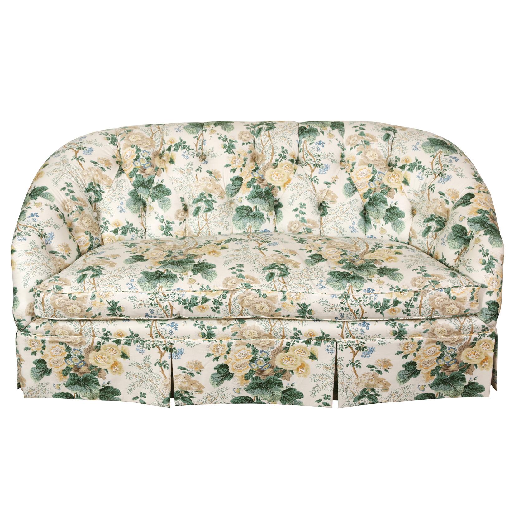 A graceful and elegant loveseat with a curved, tufted back, rolled arms, and a tailored skirt with subtle button tufting.  Upholstered in an iconic Lee Jofa chintz that can complement so many color schemes, this piece has timeless elegance.
