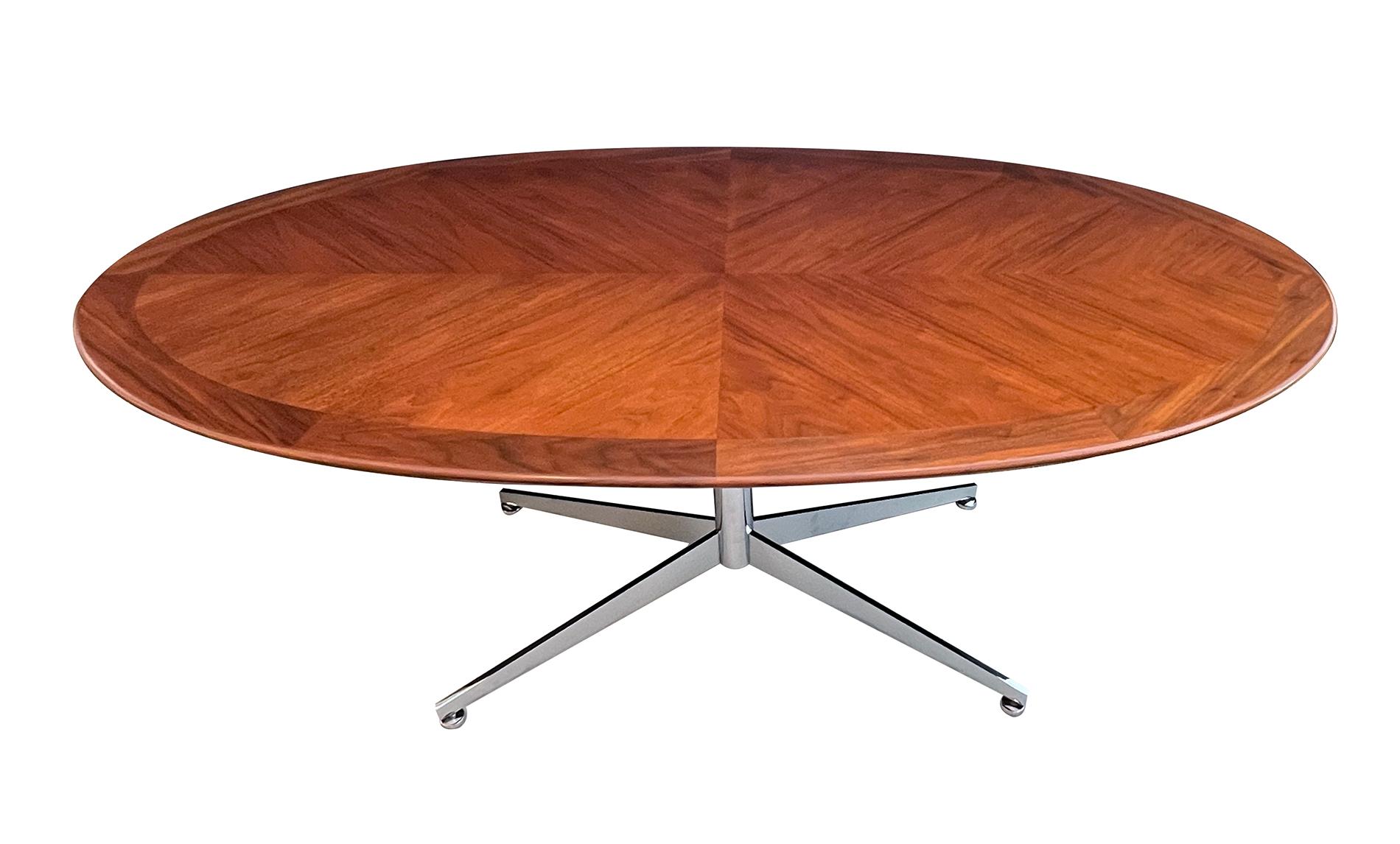 of sturdy construction consisting of a solid oval walnut top in a chevron pattern resting on a chrome quadruped base; a versatile piece that can be used as a desk, conference table or dining table; the wooden top has been professionally refinished