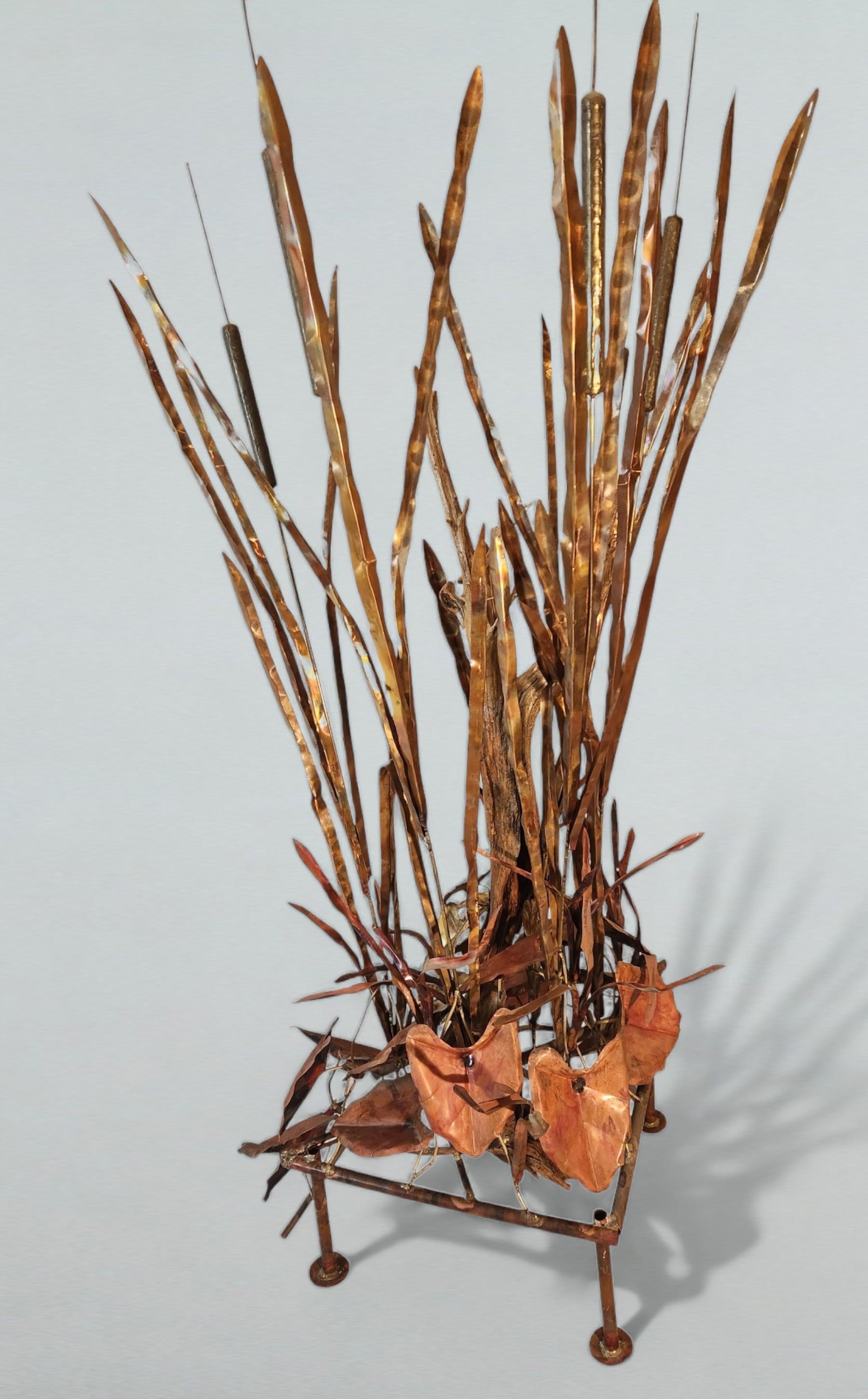 A freestanding sculpture over six feet in height in the style of Curtis Jere from the 1970s.
An interesting marsh vignette of copper and brass seagrass with cast bronze cattails and assorted leaves with a driftwood limb on a copper pipe