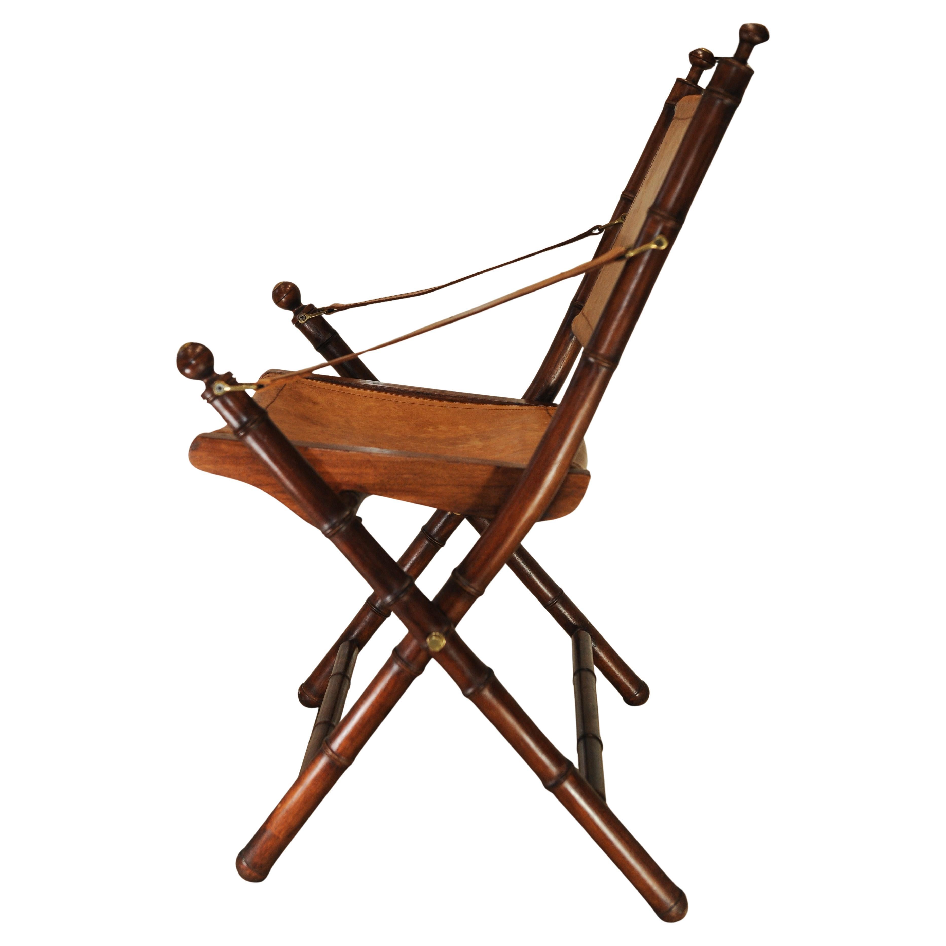 A Faux Bamboo & Stitched Tan Leather Folding Campaign Safari Chair With Sling Arms & Brass Mounts

Havana Teak and Faux Bamboo & Brass Folding Chair in the style of Maison Jansen

Height to the very top of finial 87cm 
Width at widest 58cm
Depth at