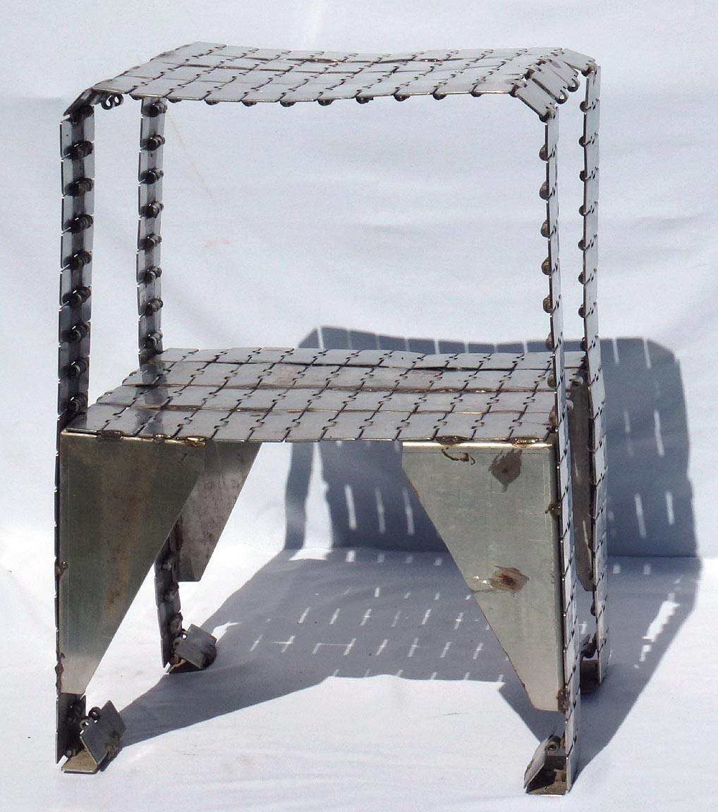 This is a folk art table hand made from stainless steel industrial conveyor belt. Each of the links was welded one by one so they would not move. The belts were found in a metal scrap yard and originally came from a candy manufacturing plant in
