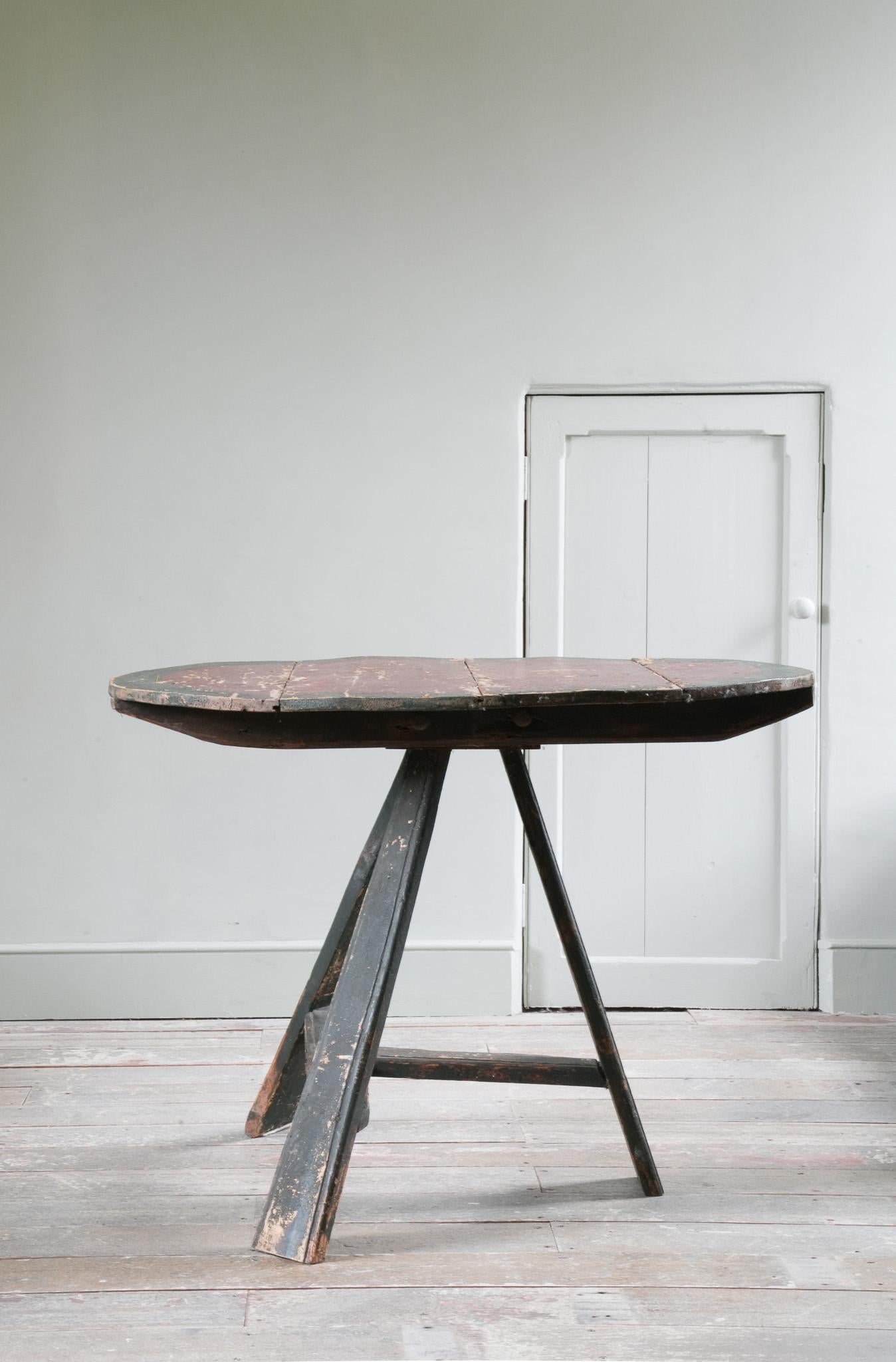 Les pieds plats, effilés et évasés, sont reliés par une traverse en T. Le plateau circulaire est composé de quatre planches.

Décoration peinte et vieillie.
