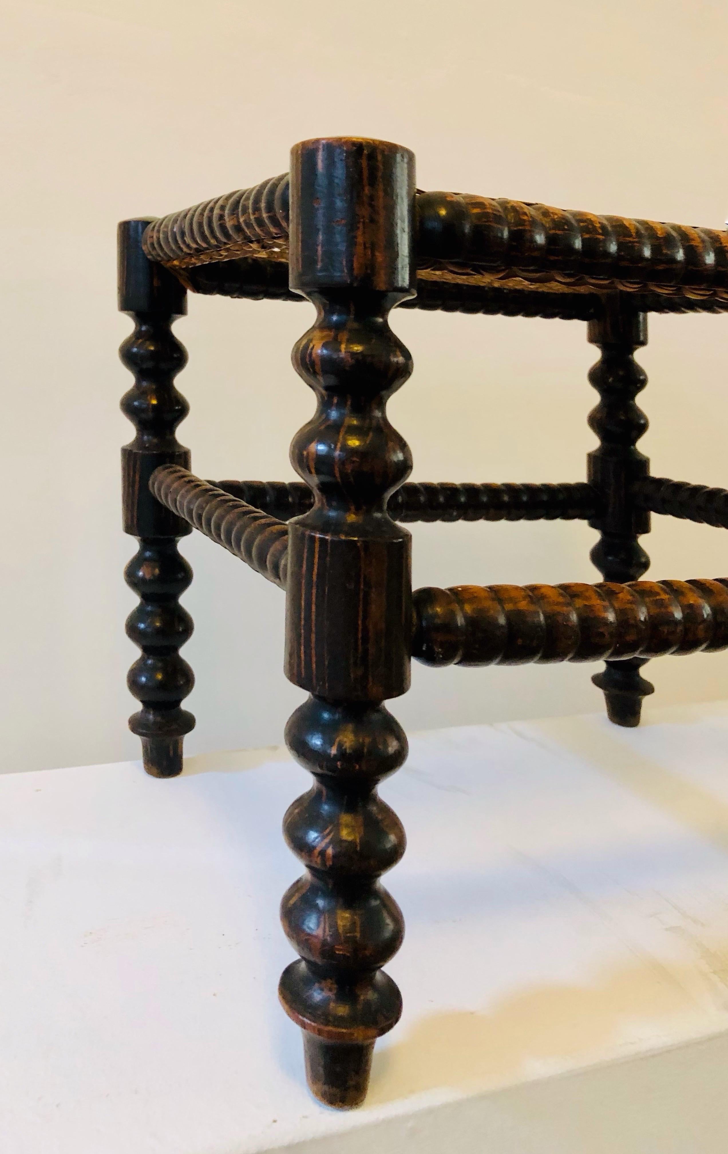 A footrest from the early 20th century, made of solid turned wood and caning. In excellent condition with a beautiful patina.