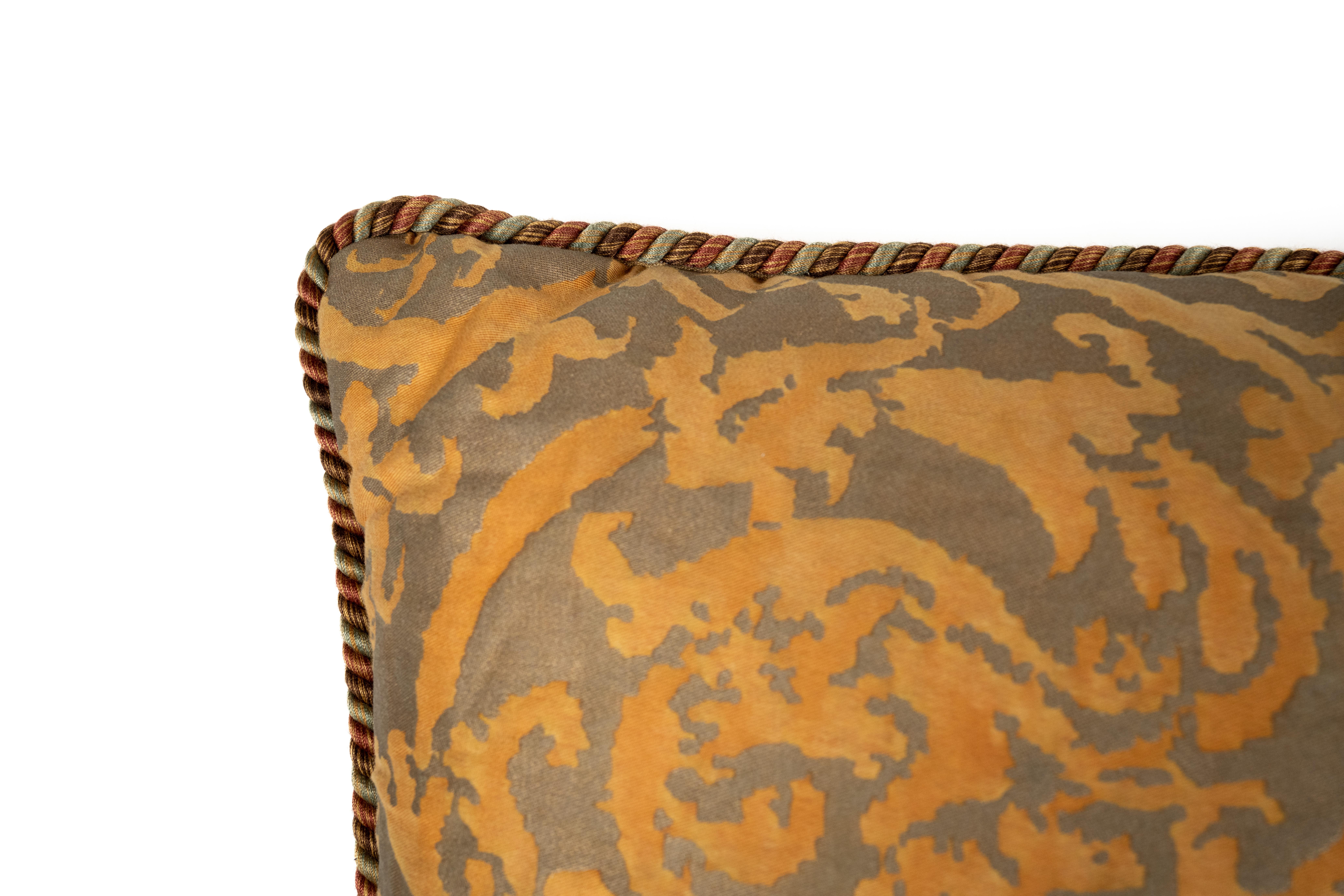 Un coussin en tissu Fortuny dans le motif Farnese, en Tangerine et Gray, une couleur abandonnée. Il est orné d'une bordure unique en forme de frange de brosse. Le motif présente un dessin de vignes torsadées et de fleurs botaniques qui est à la fois