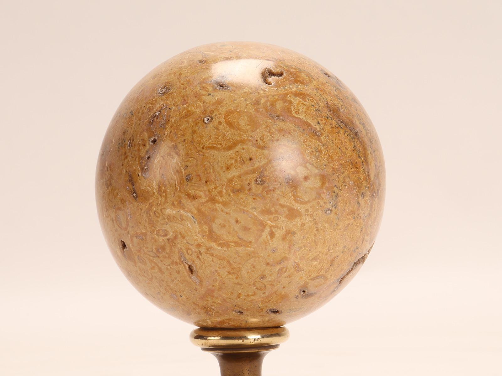 A Wunderkammer Grand Tour's souvenir. A fossil coral stone sphere, resting on a base, made of brass. Italy circa 1870.