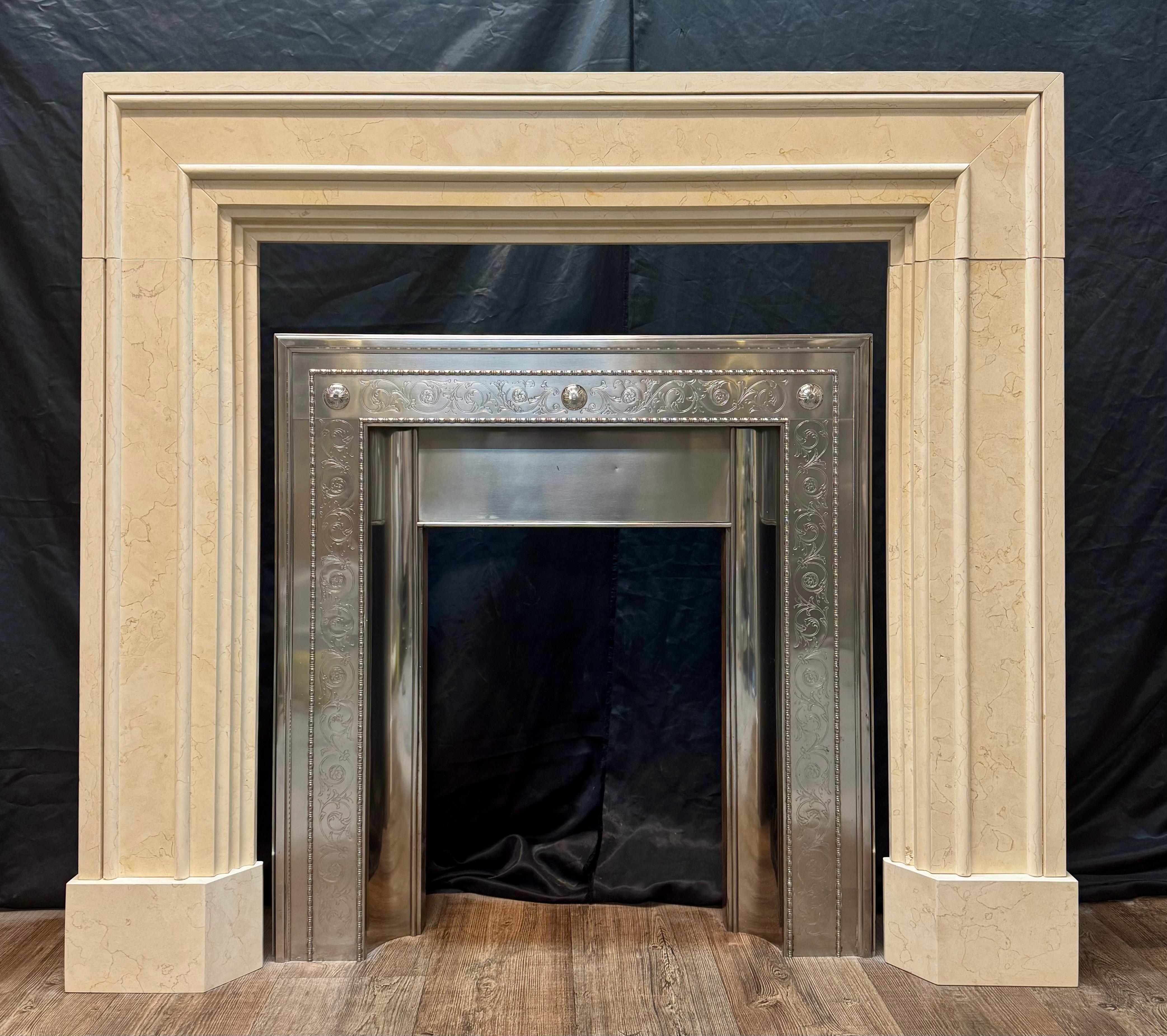 Manière Art Déco encadrée  l'entourage de la cheminée en marbre Crema Marfil poli. 

Un encadrement de cheminée bien proportionné dans le style d'une architrave encadrée, avec de généreuses sections de retour au mur, le tout reposant sur des blocs