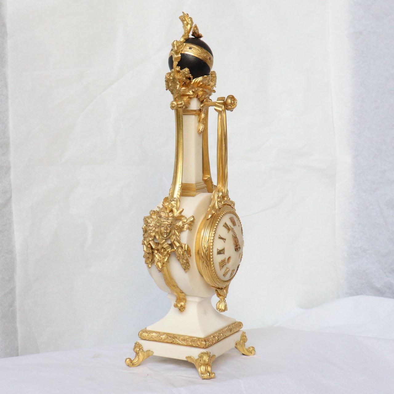 A French 19th Century Carrara Marble Mantel Clock 
Beautiful mantel timepiece in Carrara marble and mounted ormolu decorations, surmounted by blue patinated bronze globe adorned by two roosters, the sides flanked with two pairs of feminine masks,
