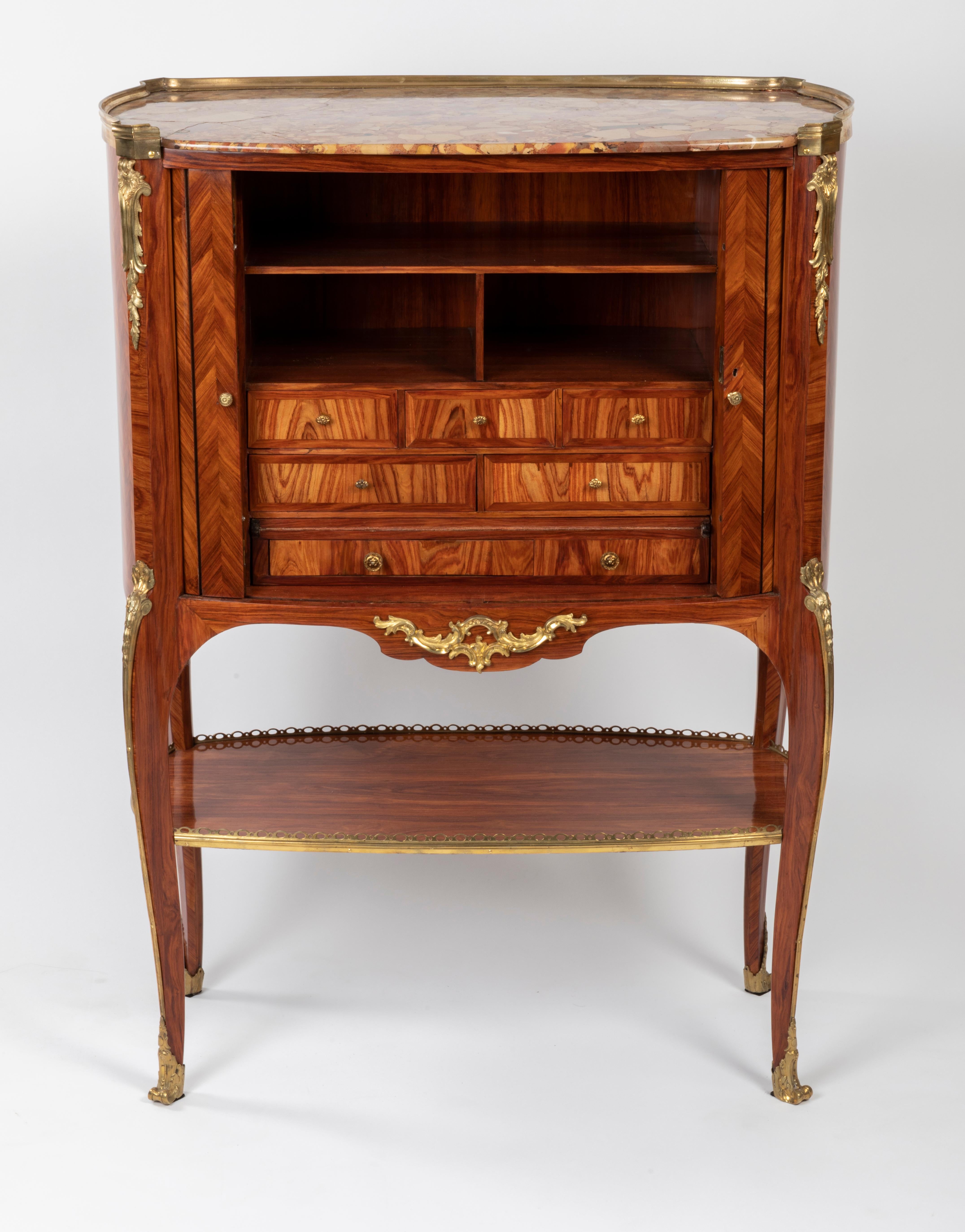 A Louis XV/XVI transitional ormolu mounted tulipwood secretaire by RVLC
Rare and elegant secretary of elliptical shape, veneered on all sides of rosewood with herringbone decoration.
It opens on the front with two sliding slatted curtains