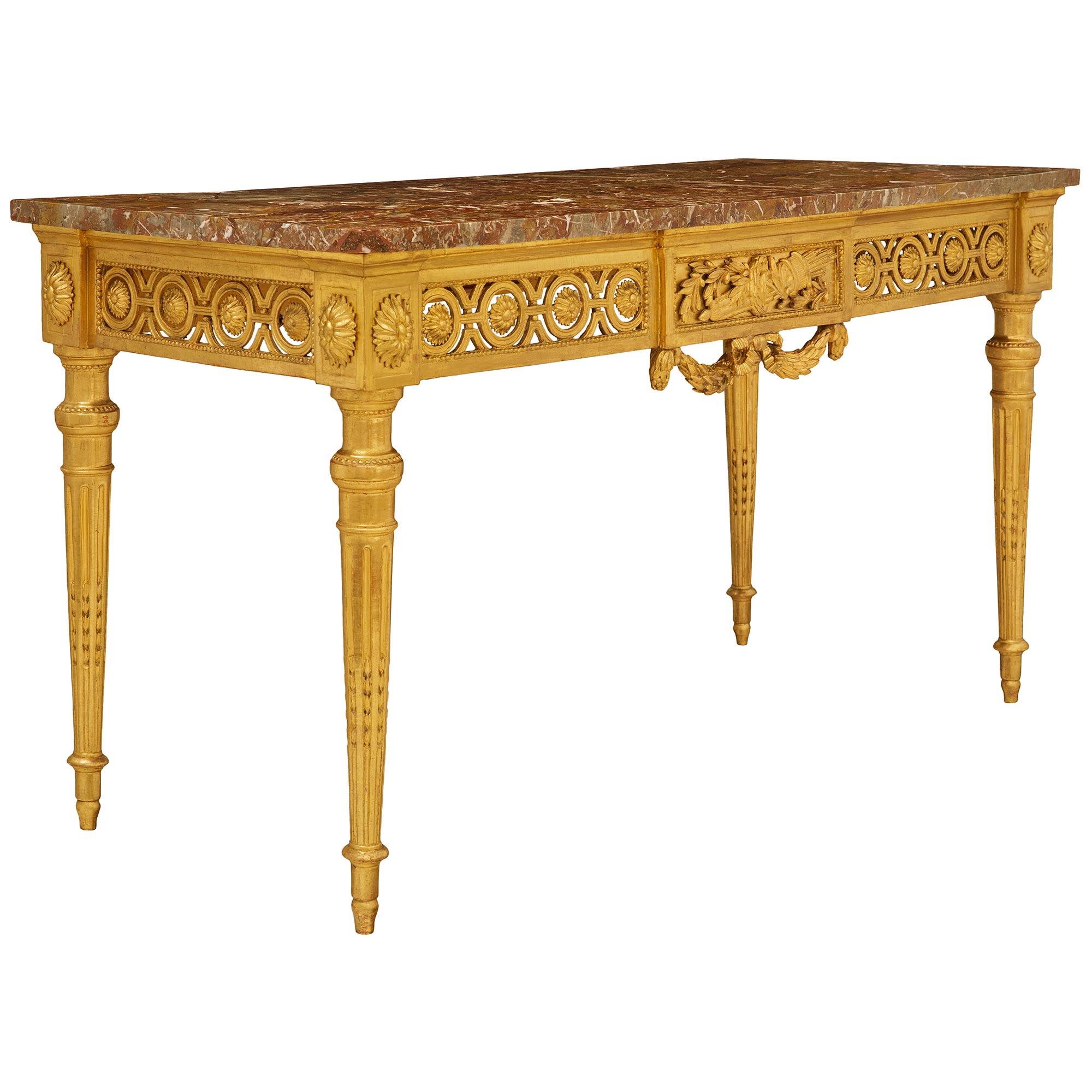An elegant and large scale French 18th century Louis XVI Period Giltwood and Sagario Marble console. The stunning freestanding console, and its original marble top, are raised by four circular tapered fluted legs with elegant chandelles in the