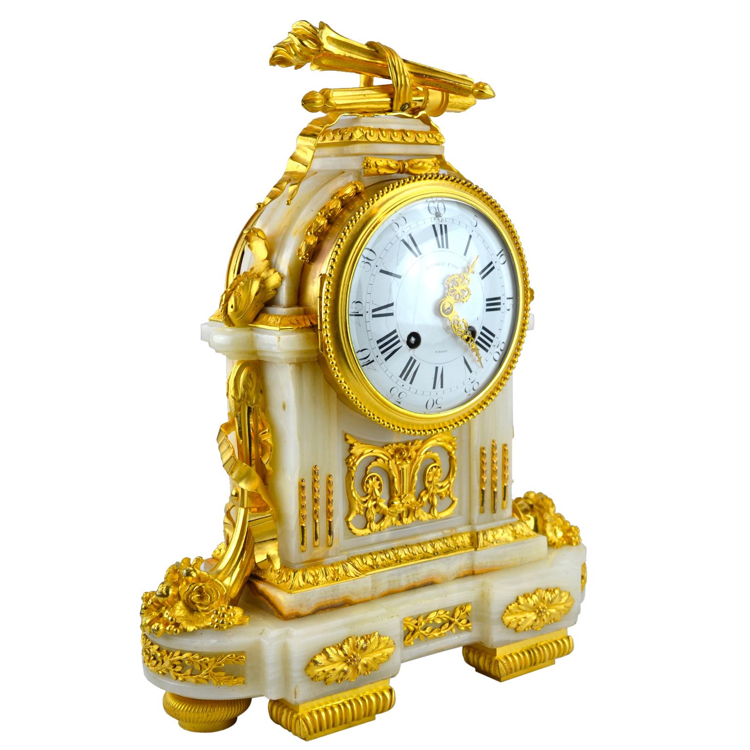 A louis XVI-style ormolu and onyx clock with a white onyx case of architectural form. The clock has fluted pilasters on each side of the dial and is highly decorated with the finest chased and gilded bronze mounts, incorporating quivers and arrows,