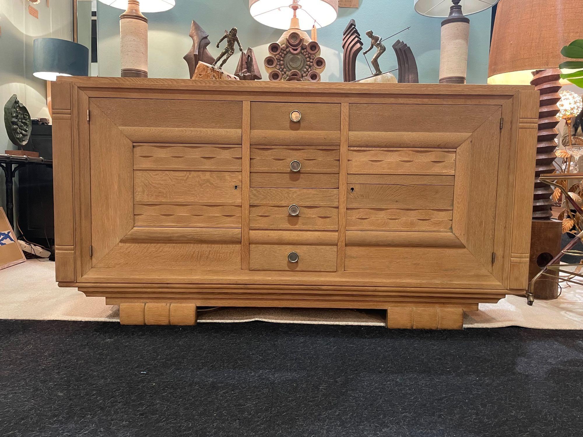 A French 1940s bleached oak sideboard with two doors and four central drawers each with orignal circular knobs. The front doors and drawers have a decorative detailed wavy relief design and there are two original brass keys.