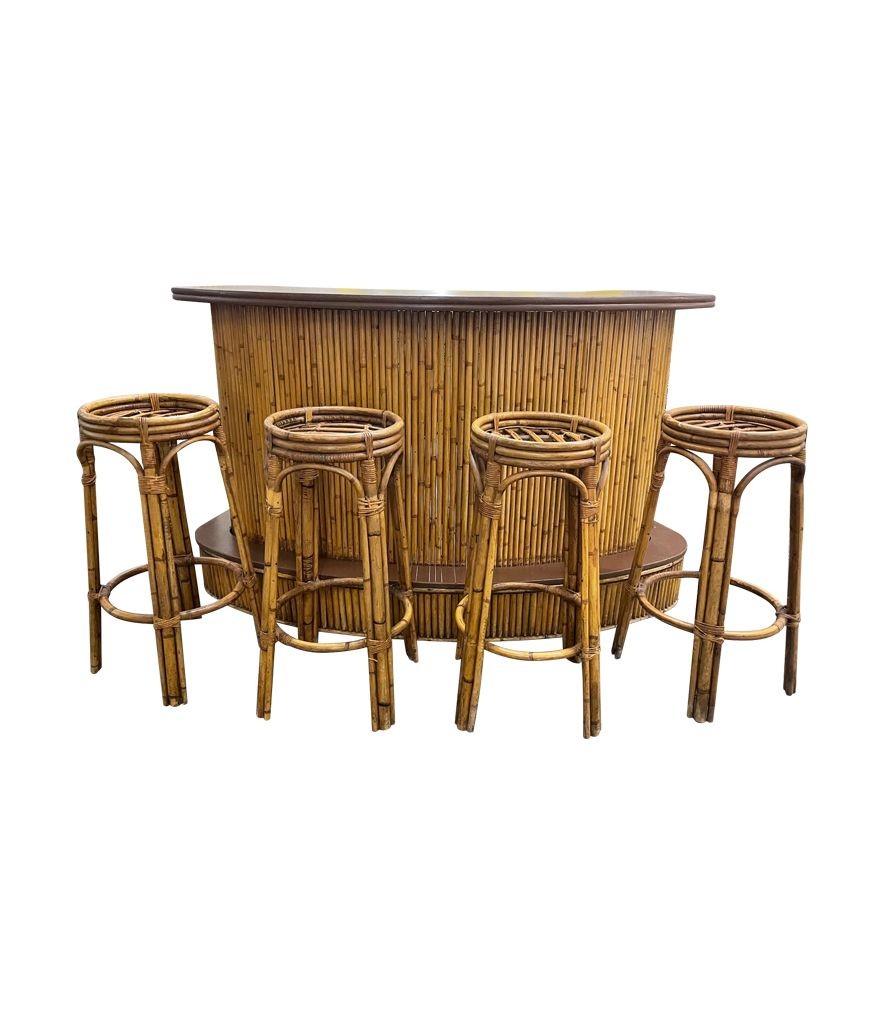 A French 1970s bamboo bar with kidney shaped wooden top, raised front foot rest with shelves and a drawer at the rear. With four orignal matching bamboo bar stools each 80cm high x 35cm diameter at the top, 54cm diameter at the base.