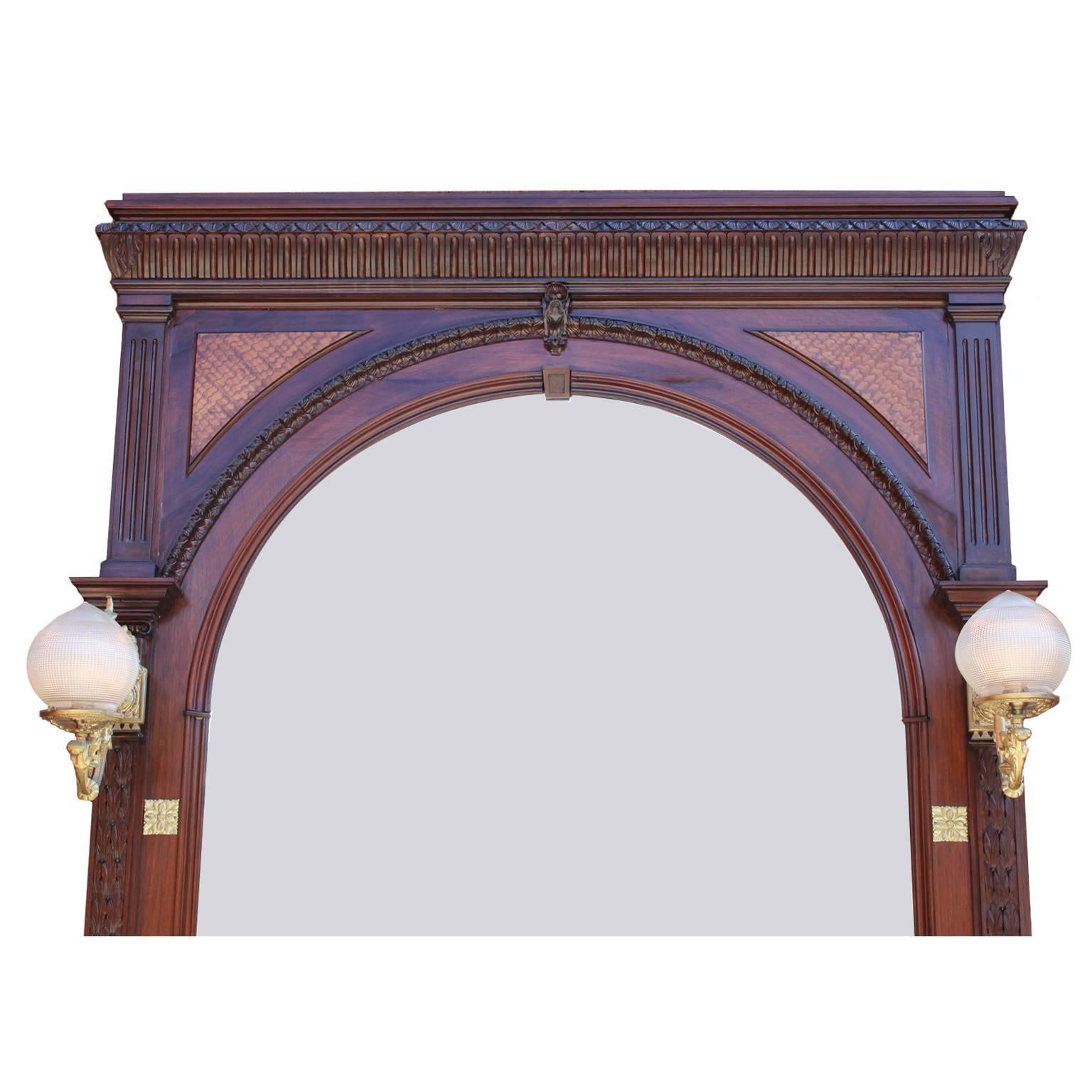 A large French 19th-20th century Louis XVI style carved mahogany and satinwood architectural mirror frame and planter. The elongated carved frame with a bevelled domed mirror, flanked by a pair of gilt-bronze single-light gasolier sconces (now