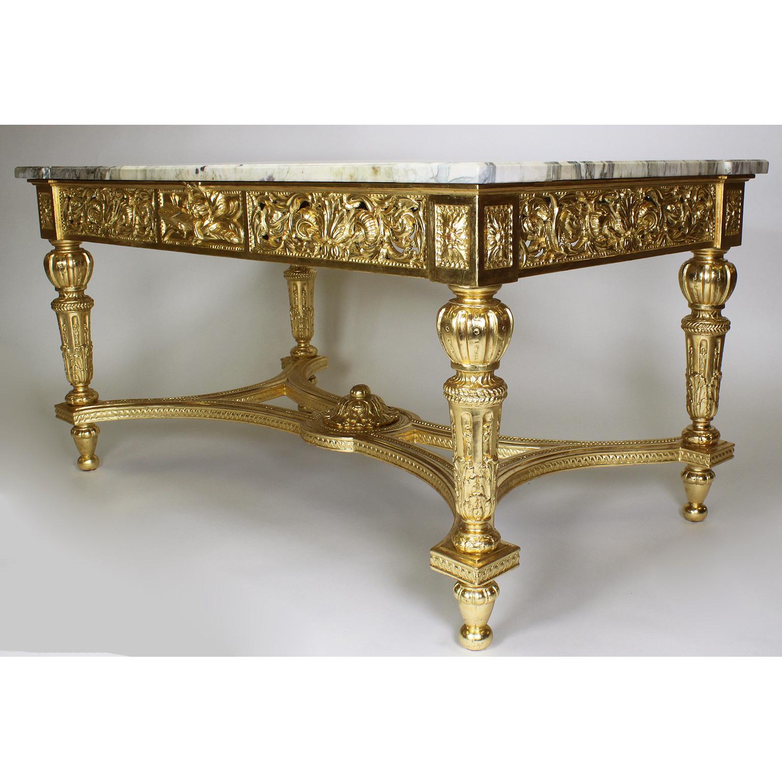 A fine French 19th-20th century Louis XVI style giltwood carved rectangular center table with marble top. The intricately giltwood carved frame with a pierced floral, acanthus and scrolled apron centered with a panel carved with a flamed quiver
