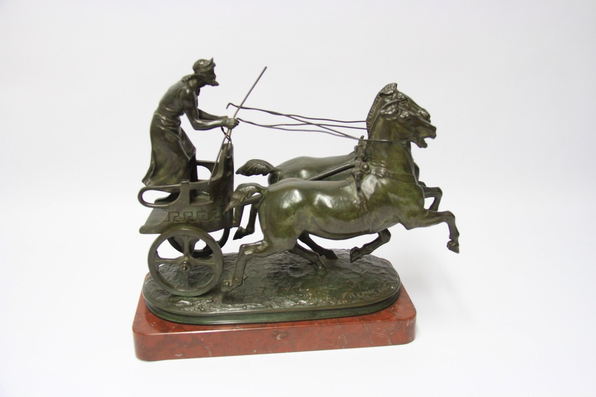 This large and decorative bronze sculpture is of a classical Grecian figure riding on a chariot pulled by two horses. It is mounted on a rouge griotte plinth. This piece was modelled by Emmanuel Fremiet, French, 1824-1910 and produced at the