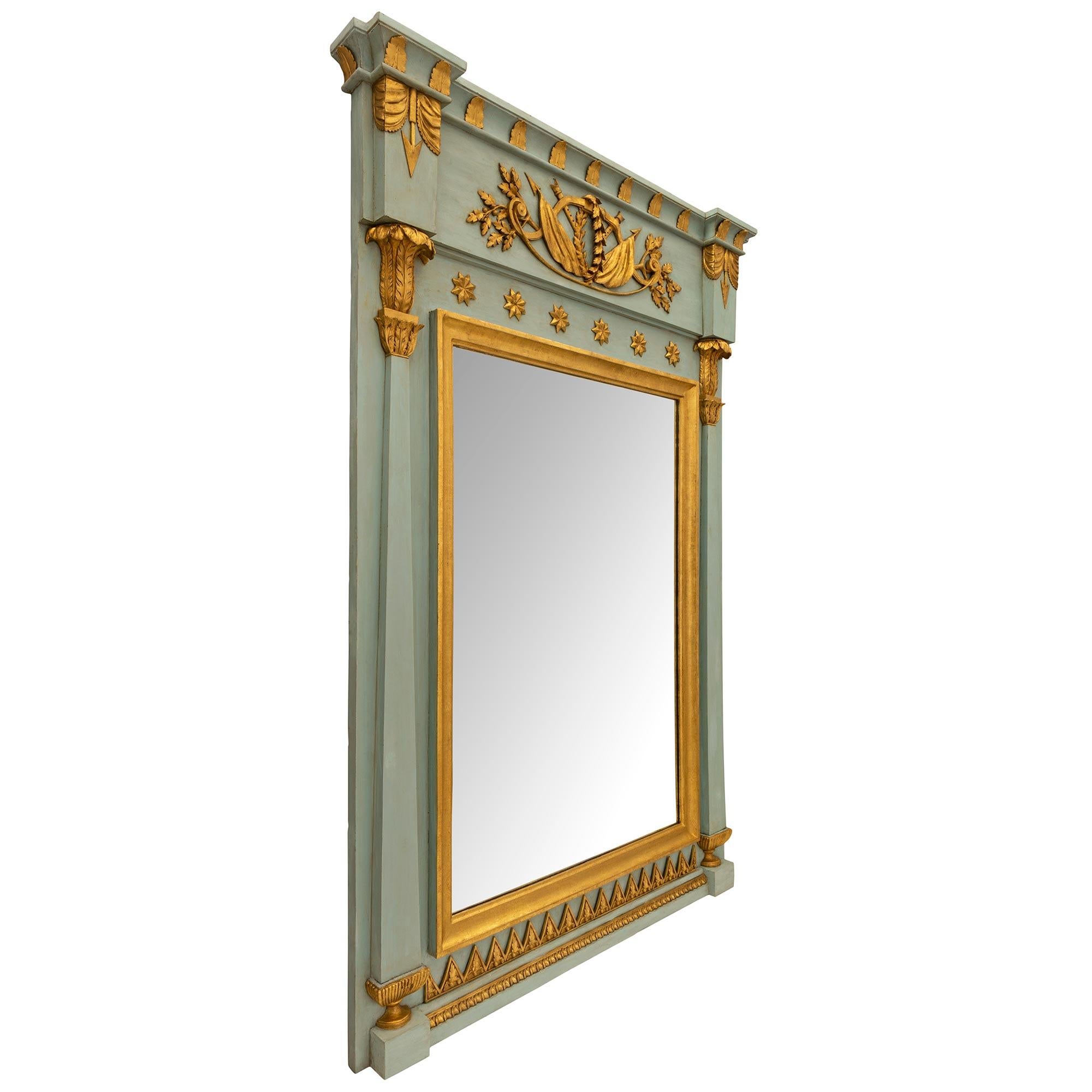 Miroir en bois patiné et doré d'époque 1er Empire, vers 1805. Le miroir présente une plaque centrale encadrée d'une élégante bordure en bois doré tacheté et flanquée de chaque côté d'étonnantes colonnes fuselées avec de fines plinthes cannelées et