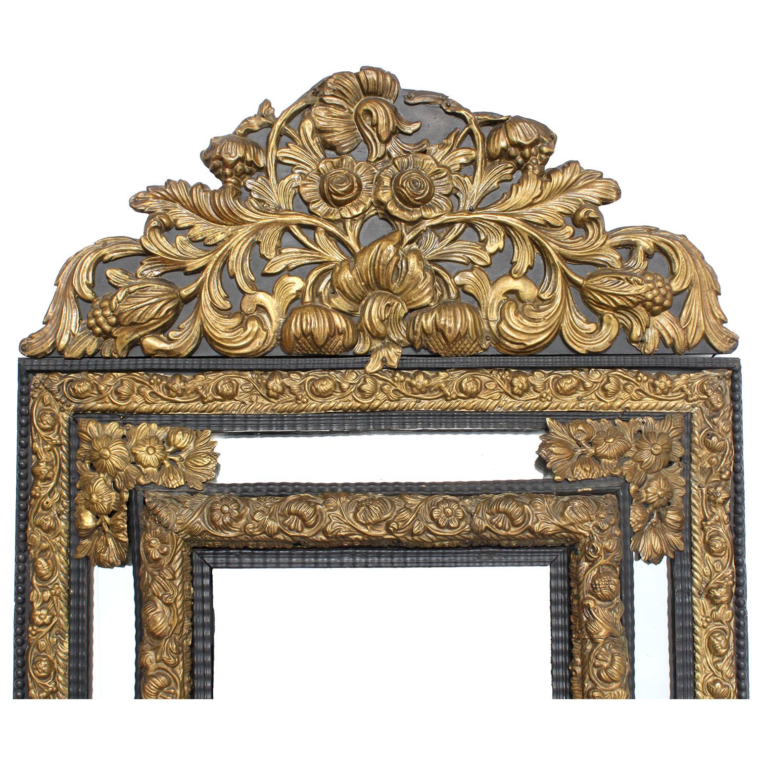 A French 19th Century Baroque Revival Style Gilt-Brass Repoussé Mirror. The ornately hammered and chased brass decorated frame, over an ebonised wooden backing, with a floral and acanthus designed. Circa: 1880.

Repoussé (French: [ʁəpuse]) or